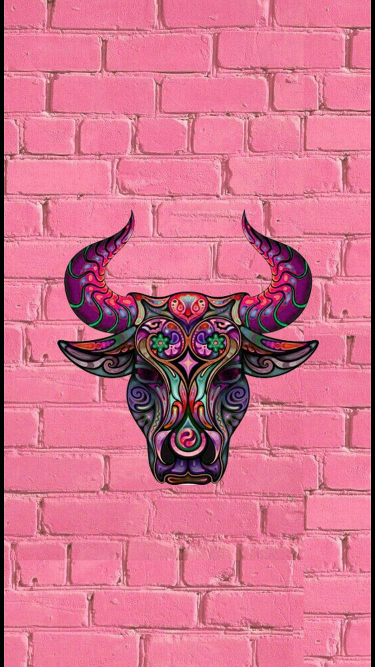 taurus 桌布 壁紙 — 一幅色彩鮮豔、帶有漩渦圖案的公牛頭骨壁畫，裝飾在明亮的粉紅色磚牆上。