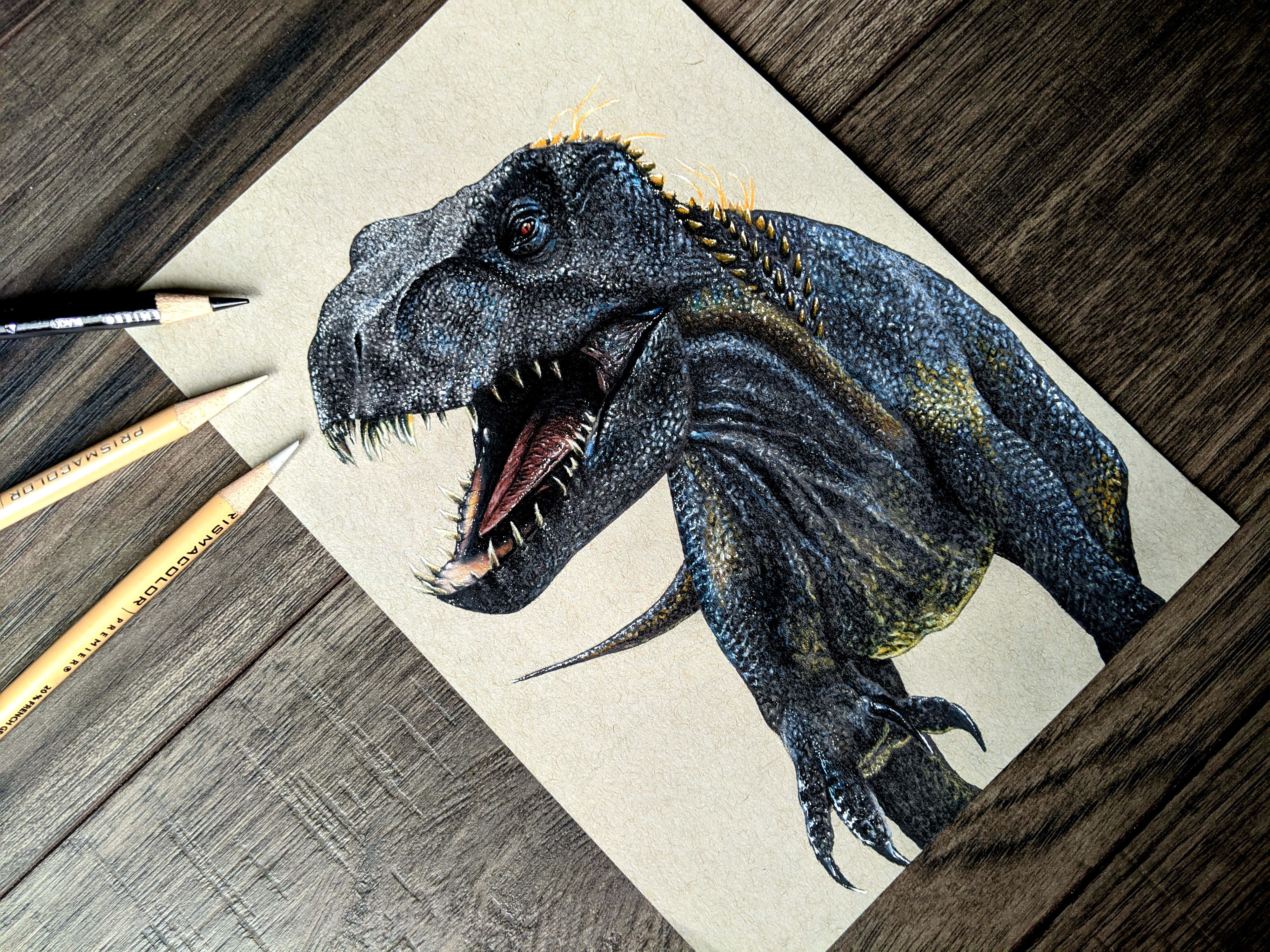 Dinosaur Drawing 桌布 壁紙 — 一幅詳細的彩色鉛筆畫，描繪一隻咆哮的霸王龍在紋理紙上，放在一張深色木桌上，旁邊有美術鉛筆。