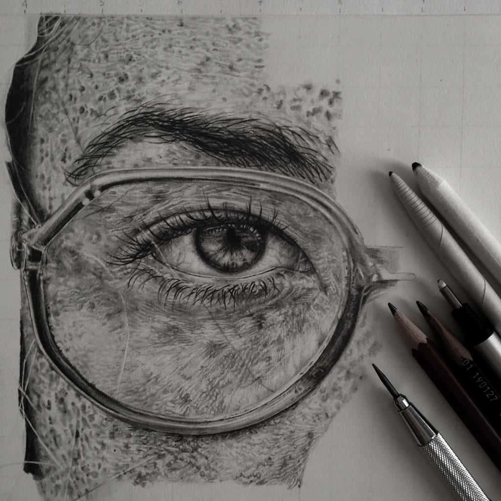 藝術 桌布 壁紙 — 一幅超寫實鉛筆素描，描繪眼鏡後的人類眼睛，帶有細緻陰影和周圍的繪畫工具。
