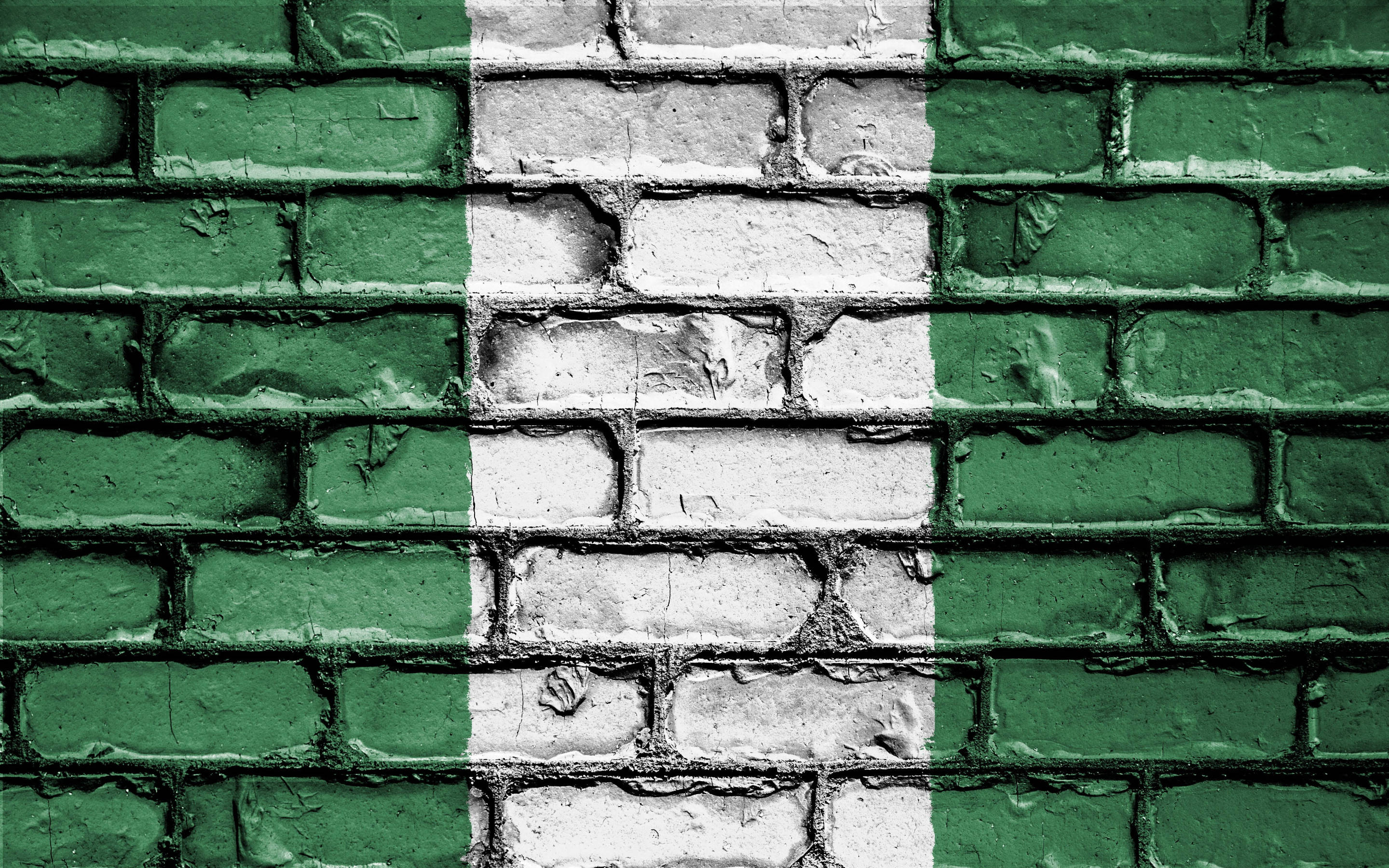 Nigeria 桌布 壁紙 — 一幅風化的磚牆，塗有奈及利亞的綠色和白色國旗條紋，顯示出剝落的紋理。