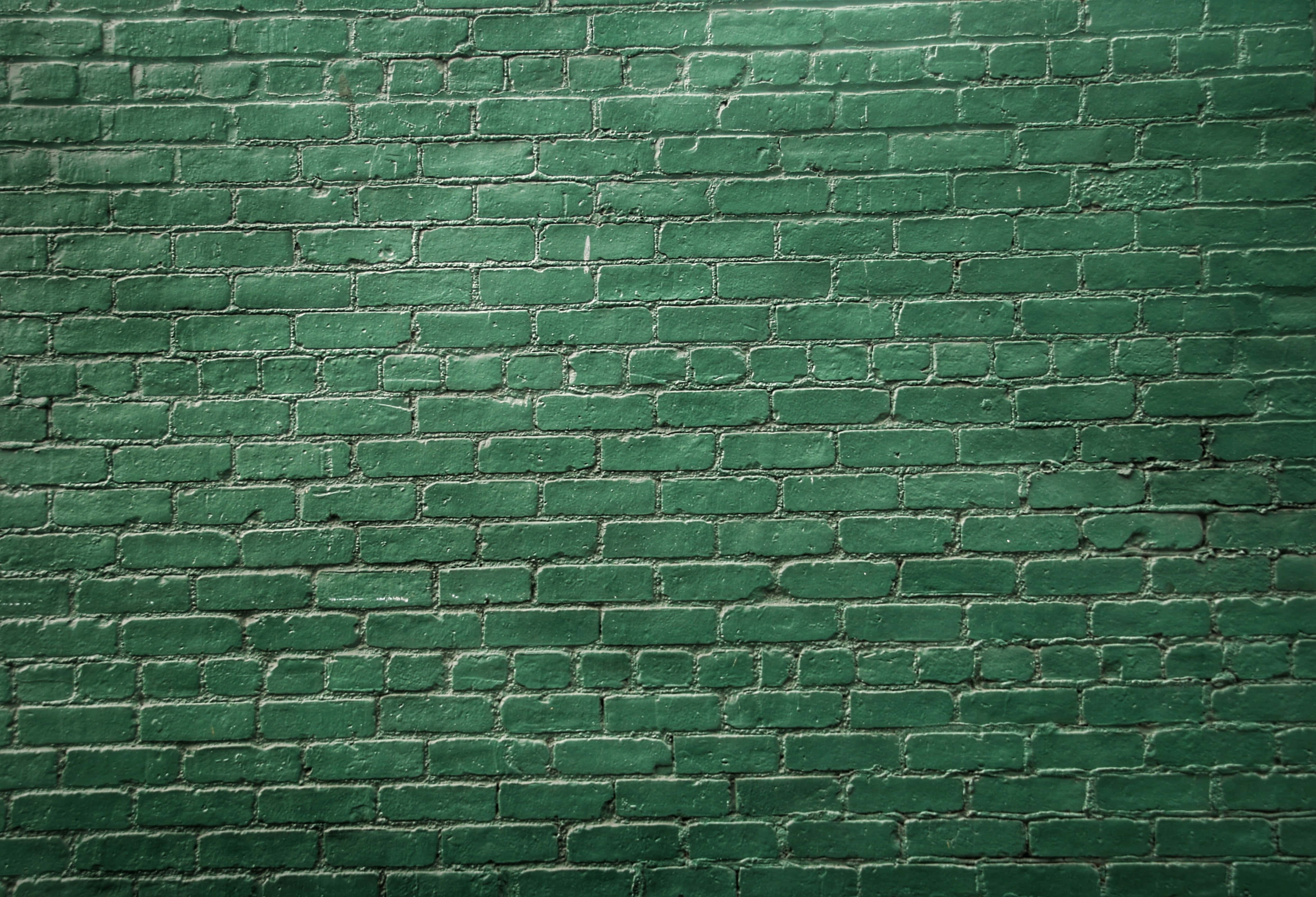 Brick Wall 桌布 壁紙 — 一幅風化的綠色油漆磚牆的特寫，具有明顯的紋理和微妙的色調變化。