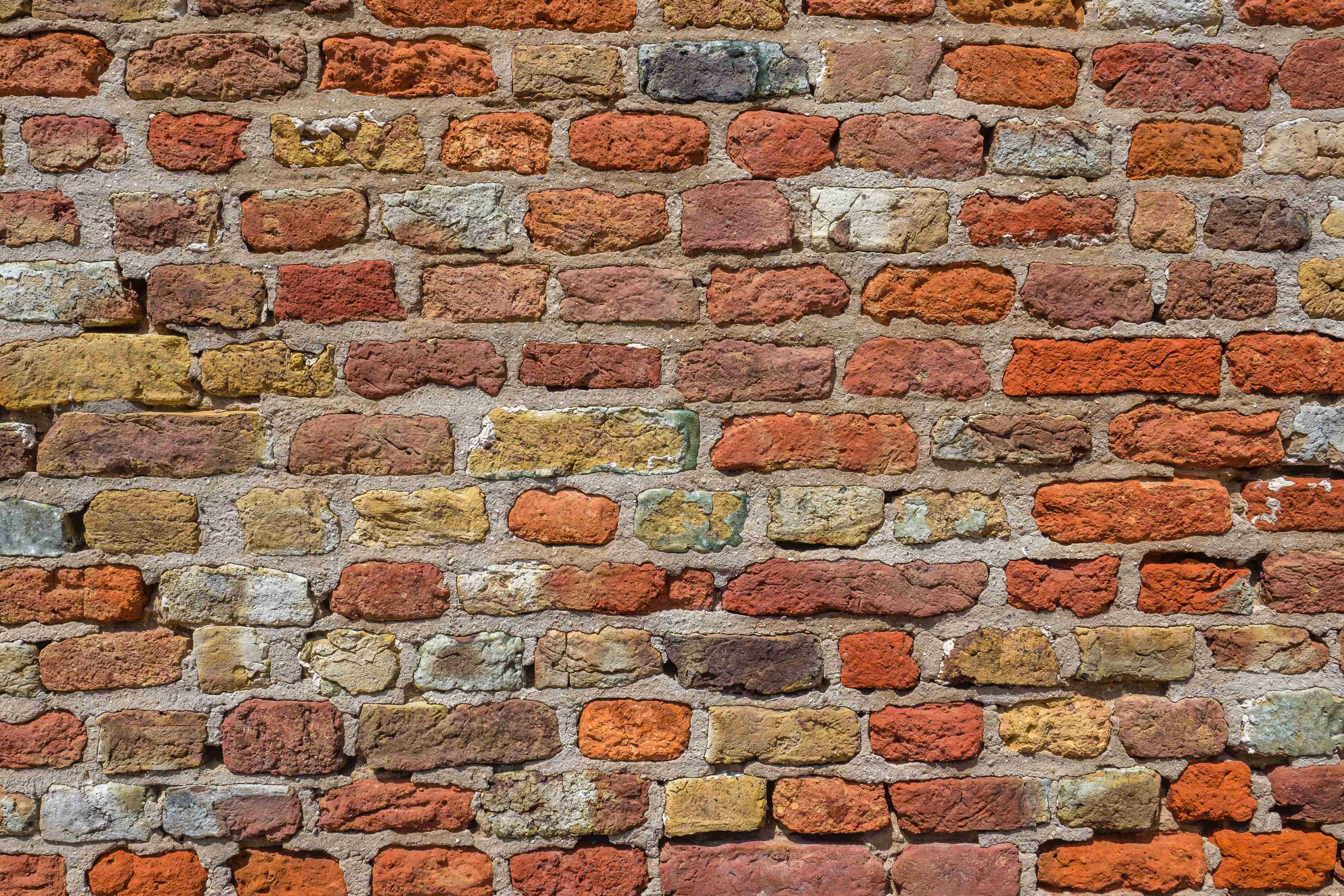 Brick Wall 桌布 壁紙 — 一幅風化磚牆的特寫，帶有各種大地色調和紋理灰泥線。