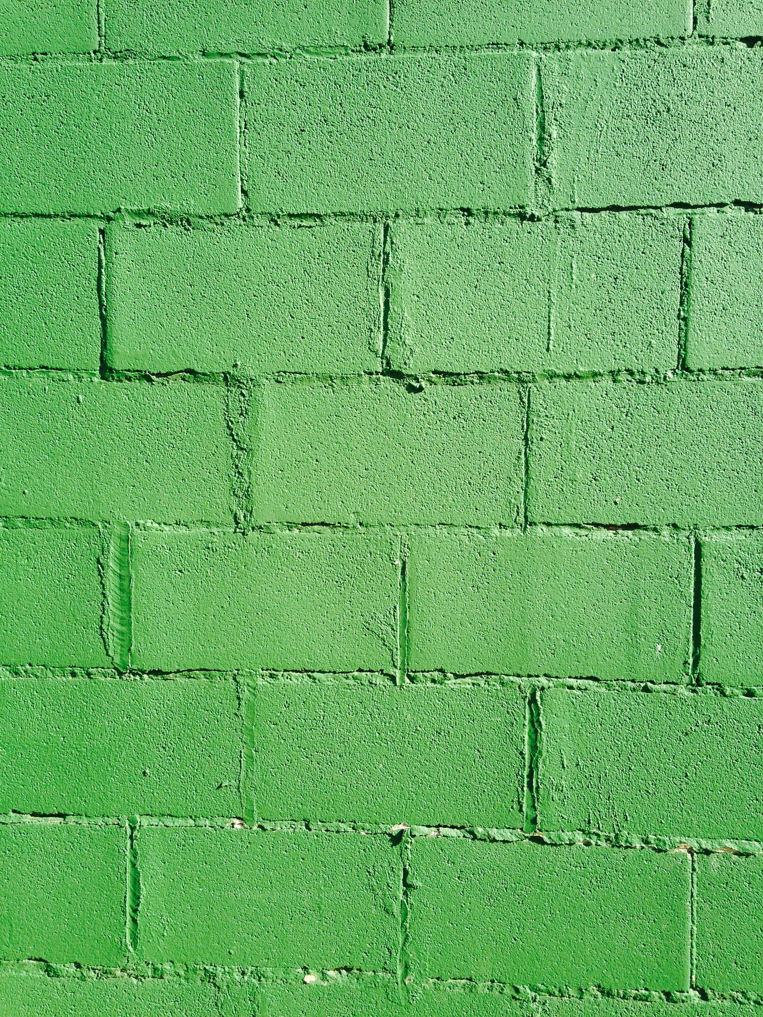 Brick Wall 桌布 壁紙 — 一幅風化磚牆的特寫，漆上鮮豔均勻的綠色，可見砂漿線條和細微紋理。