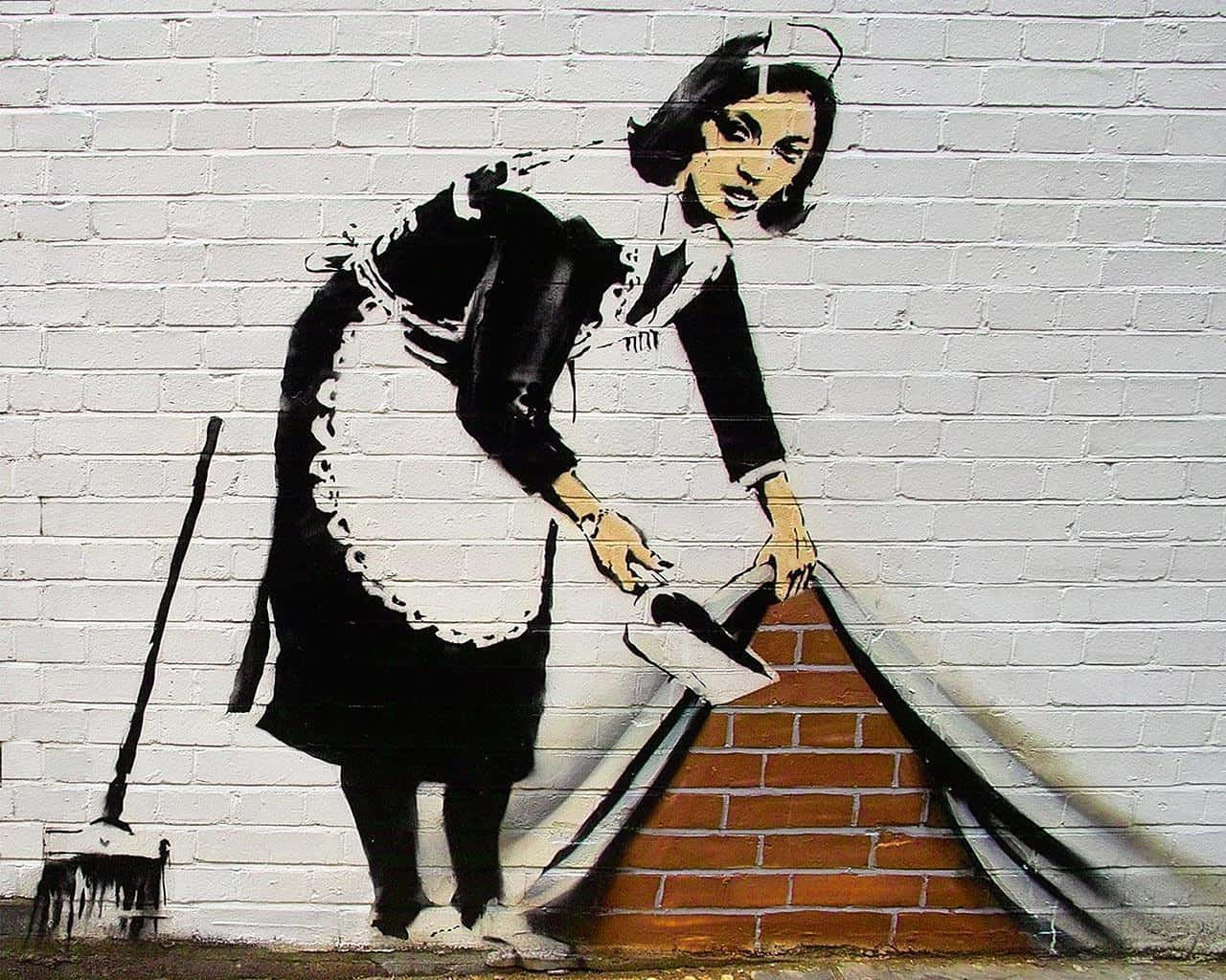 Banksy 桌布 壁紙 — 一幅鮮明的黑白街頭壁畫描繪一名女傭正在清掃磚牆，附近靠著一把掃帚。