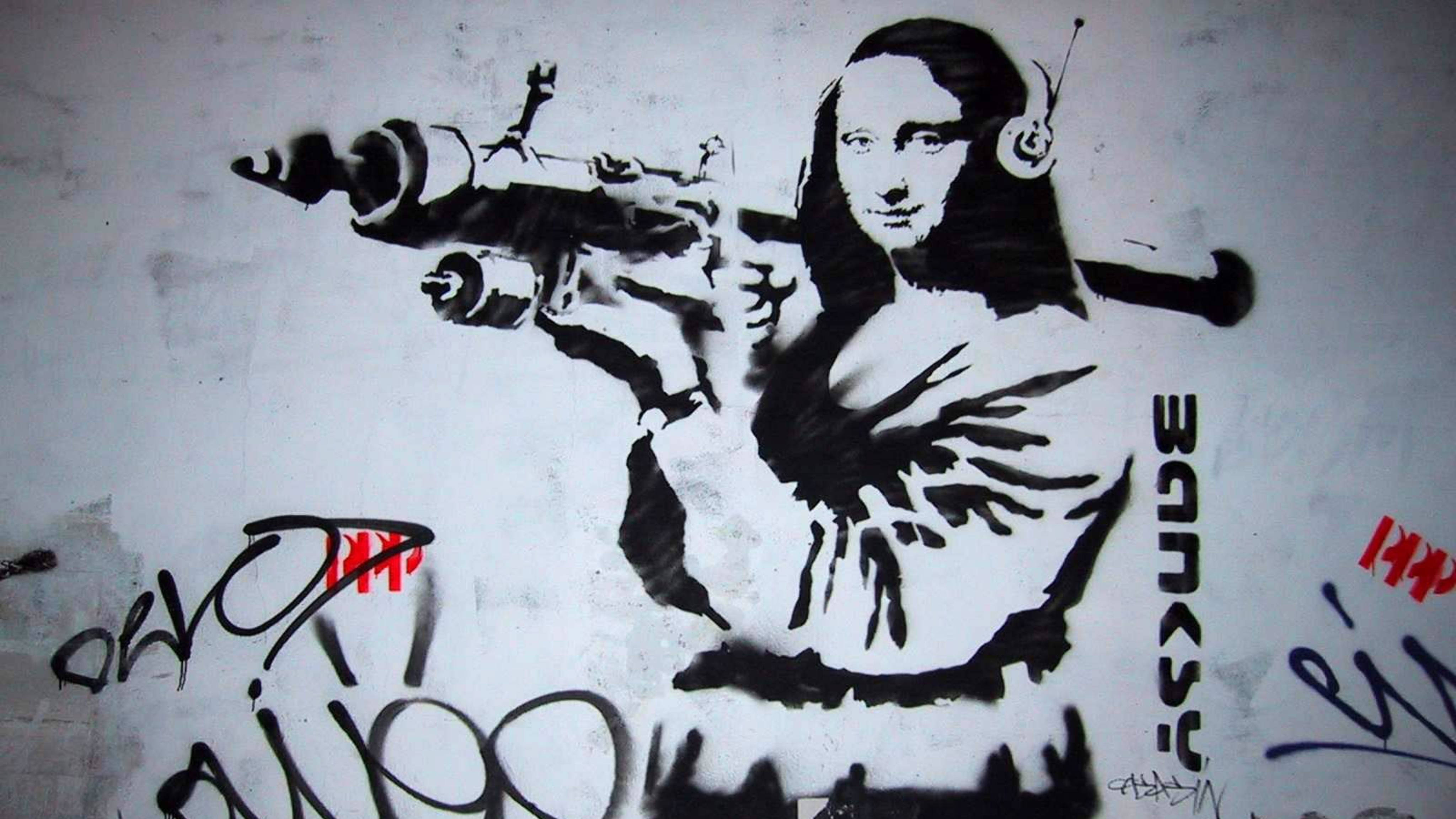 Banksy 桌布 壁紙 — 一幅黑白模板塗鴉，描繪蒙娜麗莎戴著耳機手持機關槍，位於風化牆上。