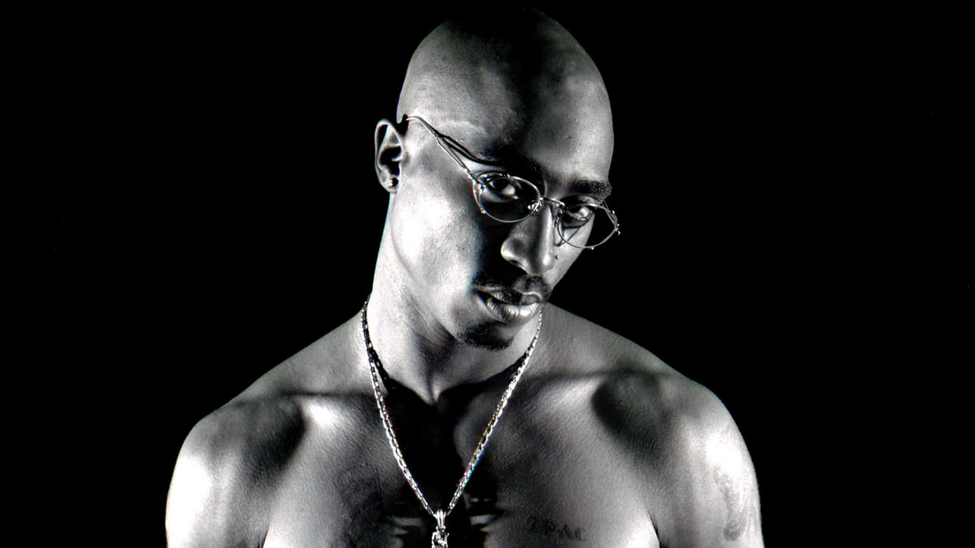 壁紙 — 一幅黑白肖像，Tupac Shakur 戴著眼鏡和鏈條，背景深色。
