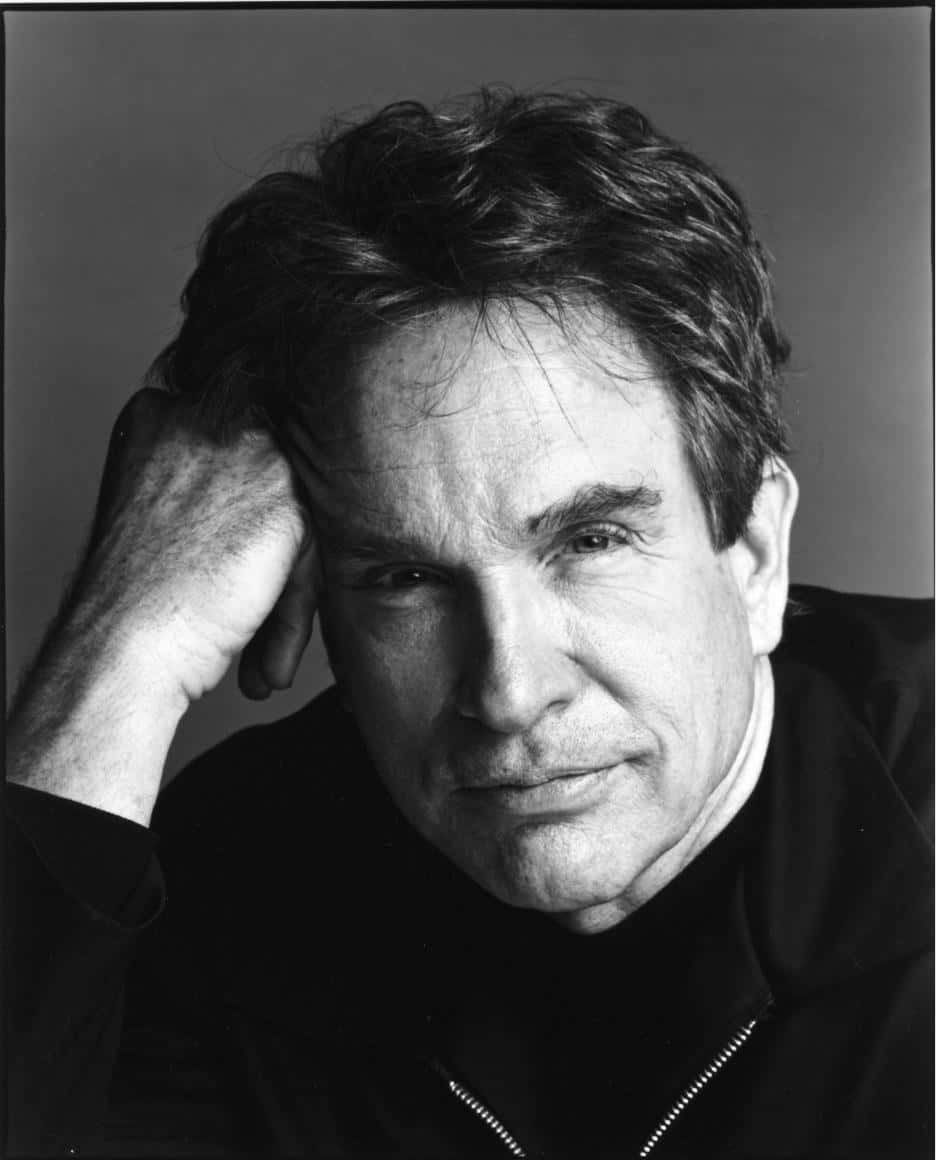 Warren Beatty 桌布 壁紙 — 一幅黑白肖像，一名頭髮蓬亂的男子將頭靠在手上，背景簡潔。