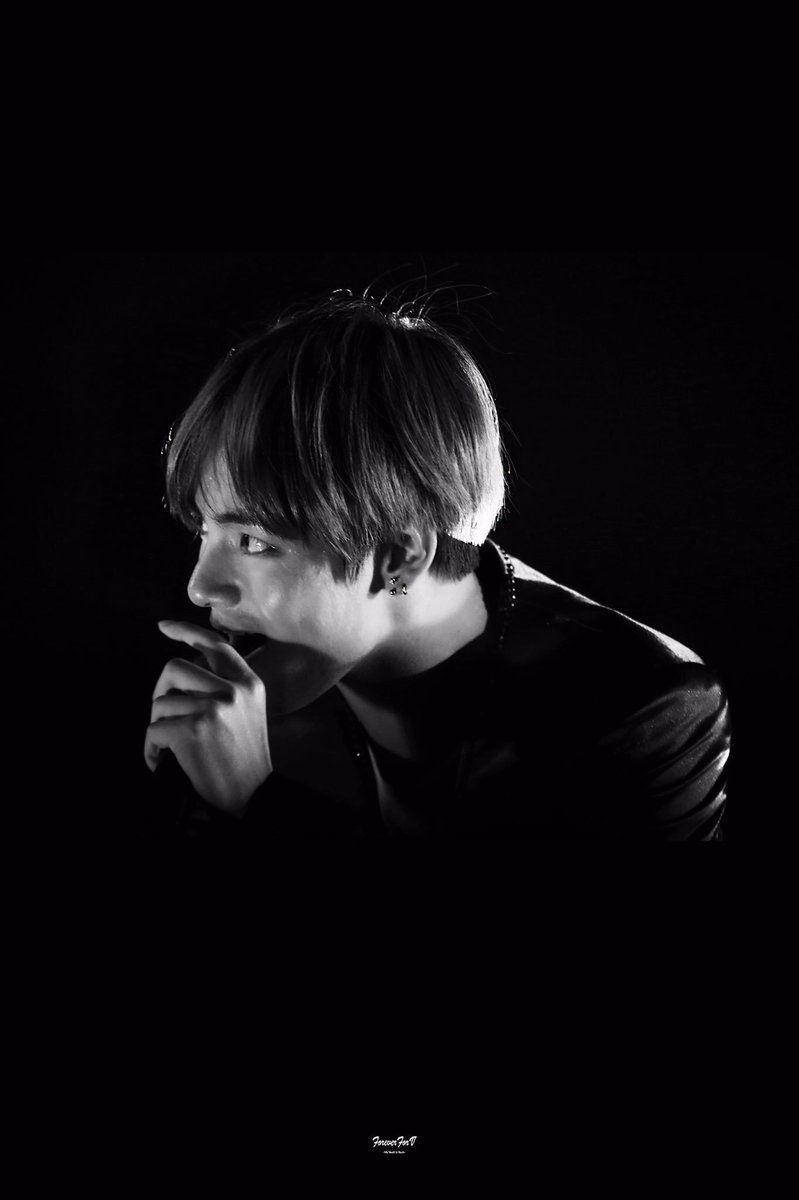 Bts Black 桌布 壁紙 — 一幅黑白肖像，年輕男子側面輪廓，背景深色，手靠近嘴邊，從側面戲劇性地打光。