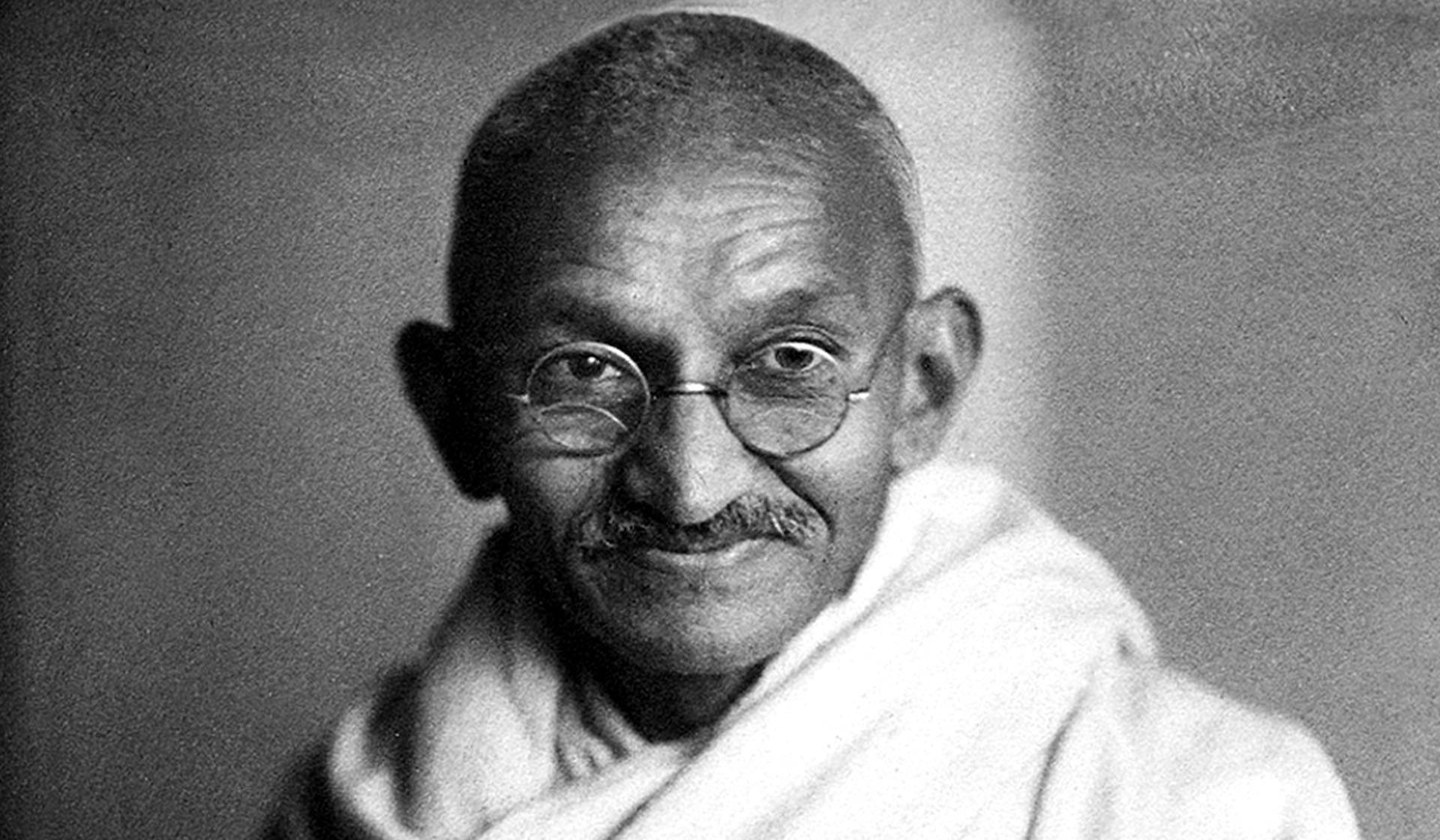 Mahatma Gandhi 桌布 壁紙 — 一幅黑白肖像，描繪聖雄甘地戴著圓框眼鏡，披著白色披肩，溫柔微笑。