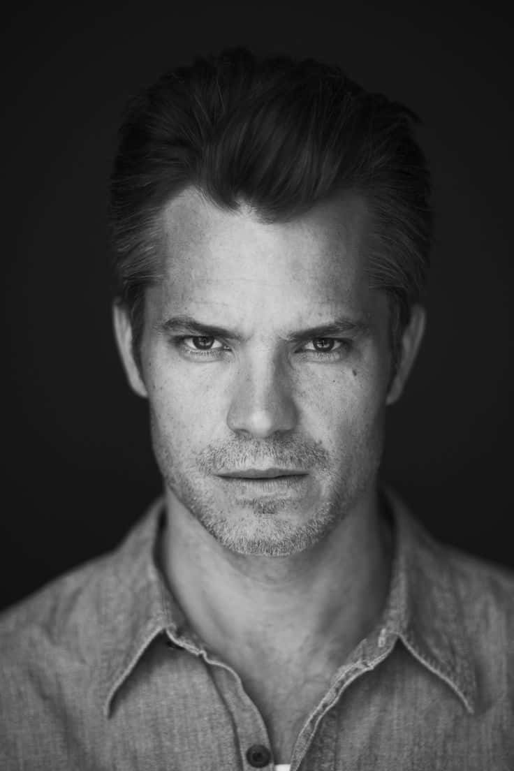 timothy olyphant 桌布 壁紙 — 一幅黑白肖像照，一名眼神銳利、鬍渣濃密的男子在深色背景下直視鏡頭。