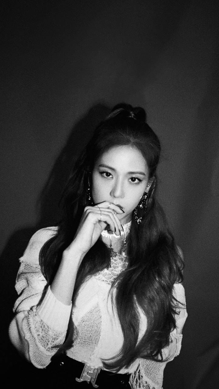 Jisoo Cute 桌布 壁紙 — 一幅黑白肖像照，長髮女性在深色背景前將手靠近嘴唇，若有所思地擺姿勢。