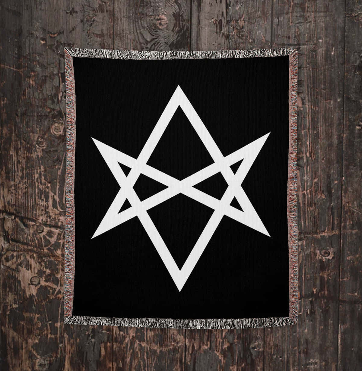 Thelema 桌布 壁紙 — 一幅黑色編織掛毯，上面有白色五角星符號，掛在風化的木牆上。