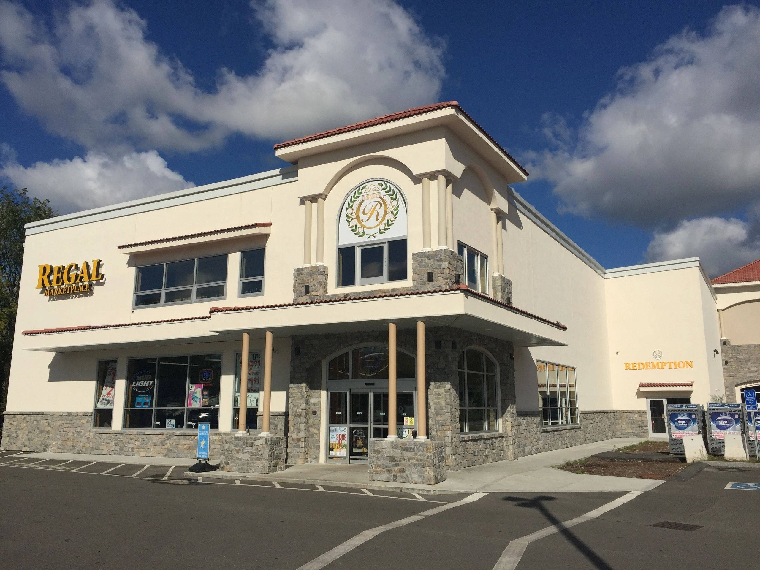 Building 桌布 壁紙 — 一座Regal Cinemas戲院建築，米色灰泥石外牆，上方是明亮的藍天和蓬鬆的白雲。