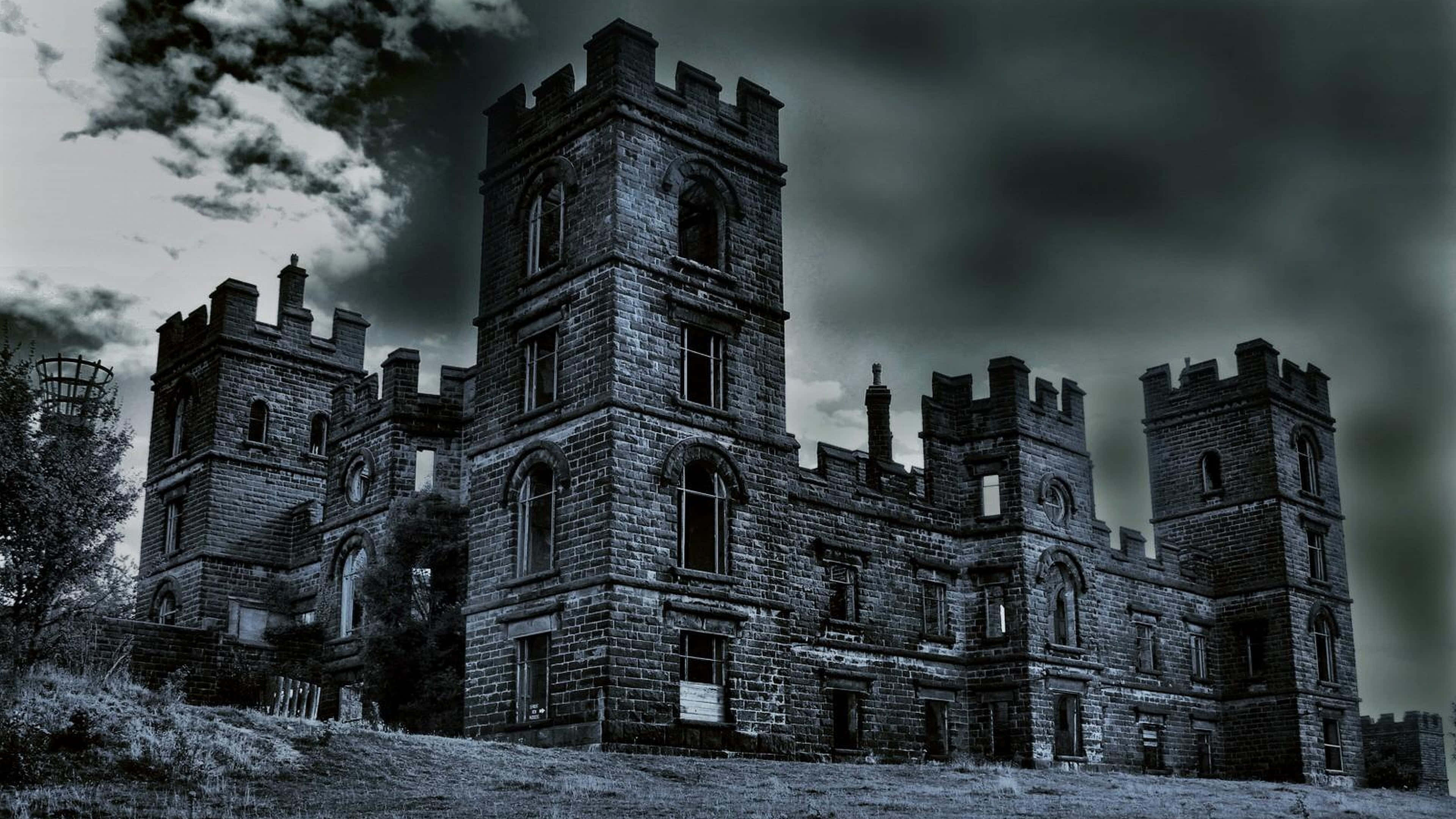 haunted 桌布 壁紙 — 一座令人毛骨悚然的風化石頭城堡，帶有破碎的窗戶和鋸齒狀的塔樓，矗立在陰沉、暴風雨的天空下。