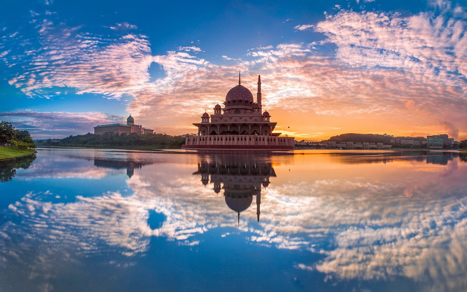 Malaysia 桌布 壁紙 — 一座令人驚嘆的粉紅色清真寺完美地倒映在平靜的水面上，天空是充滿活力的日落，帶有條紋狀的雲彩。
