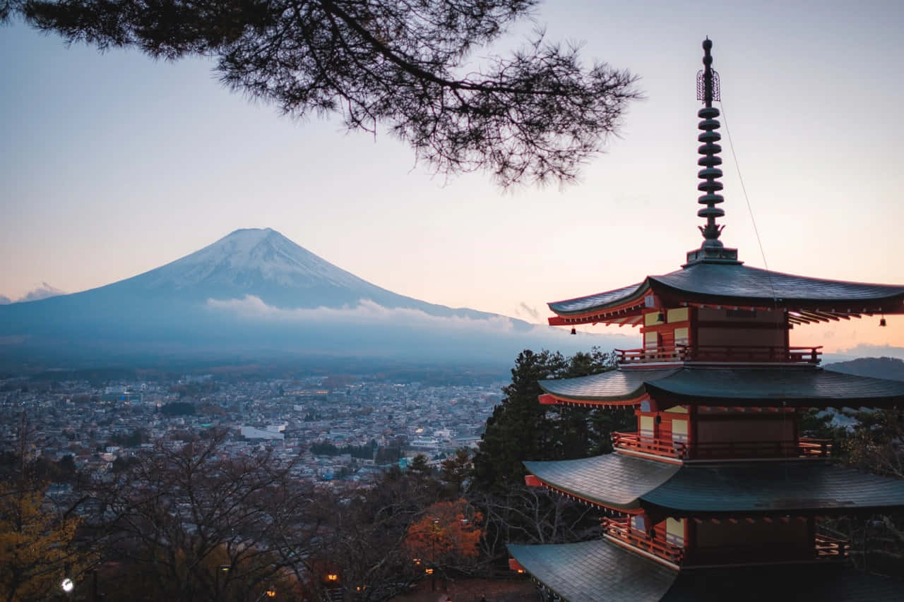 Beautiful Travel 桌布 壁紙 — 一座傳統日本寶塔矗立在前景，富士山的雪頂山峰在黃昏時分從霧氣瀰漫的小鎮後方升起。