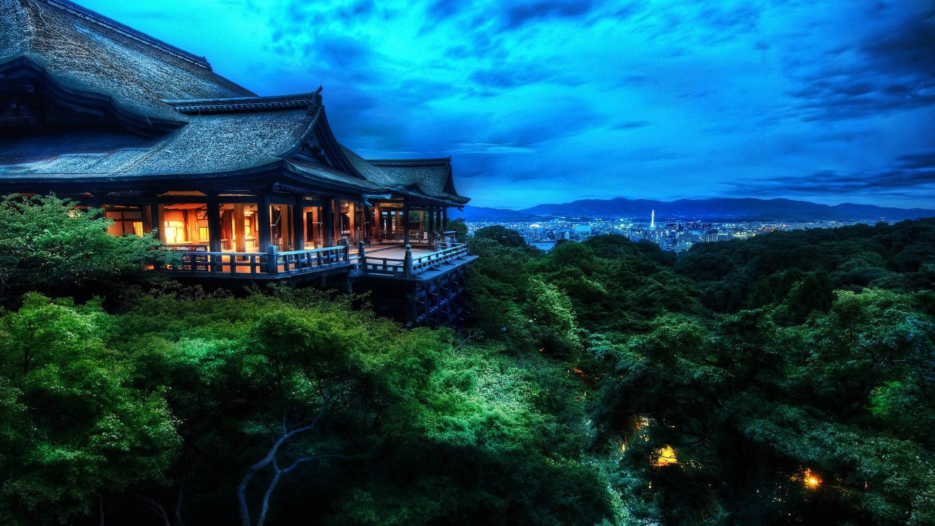 日式自然壁紙 桌布 壁紙 — 一座傳統日本寺廟坐落在茂密綠樹之上，俯瞰著深藍色暮色天空下的廣闊城市景觀。