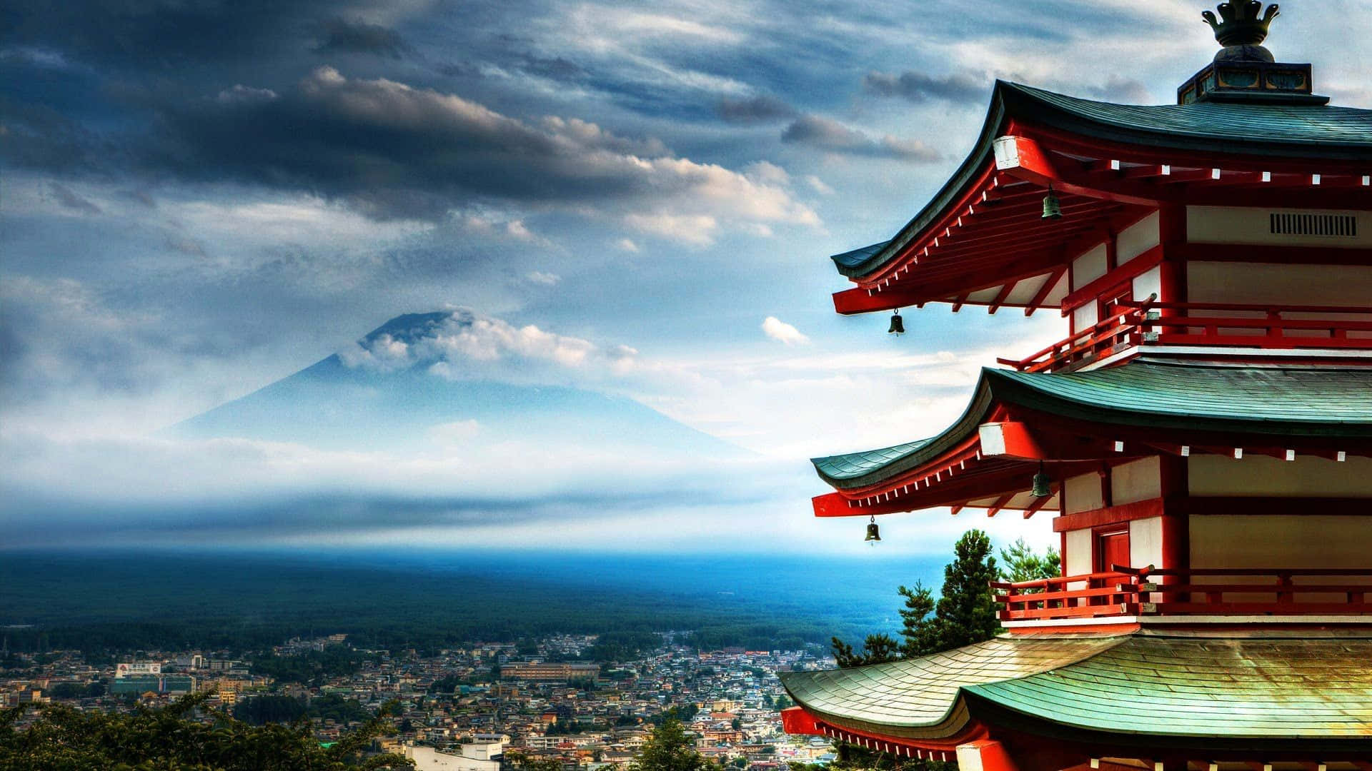 Relaxation 桌布 壁紙 — 一座傳統的紅色日本寺廟俯瞰著霧氣瀰漫的城市景觀，富士山在戲劇性的多雲天空下雄偉地聳立在遠方。