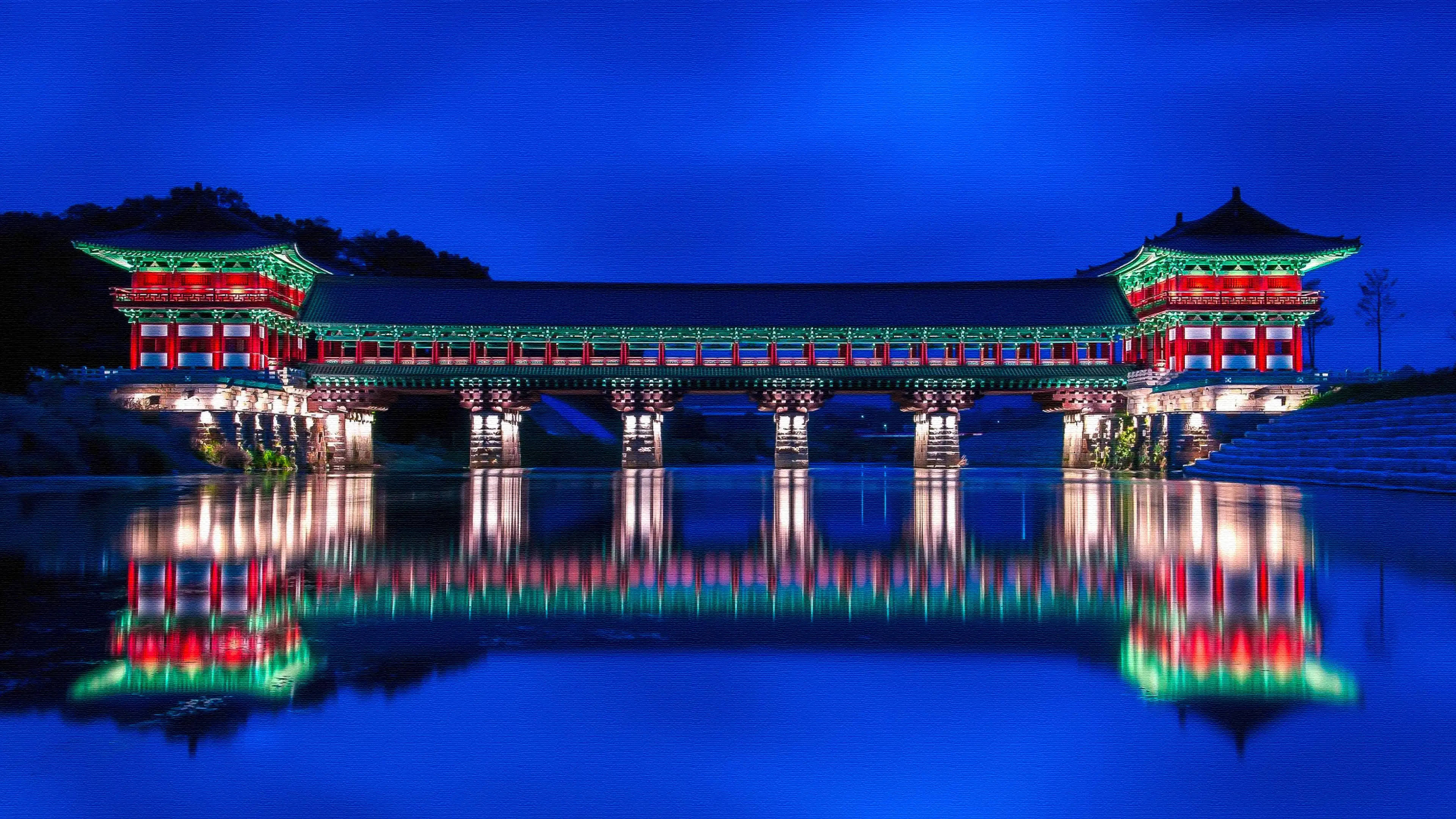 韓國 桌布 壁紙 — 一座傳統韓國亭閣橋在深藍色夜空下，於平靜水面上閃爍著紅綠燈光。