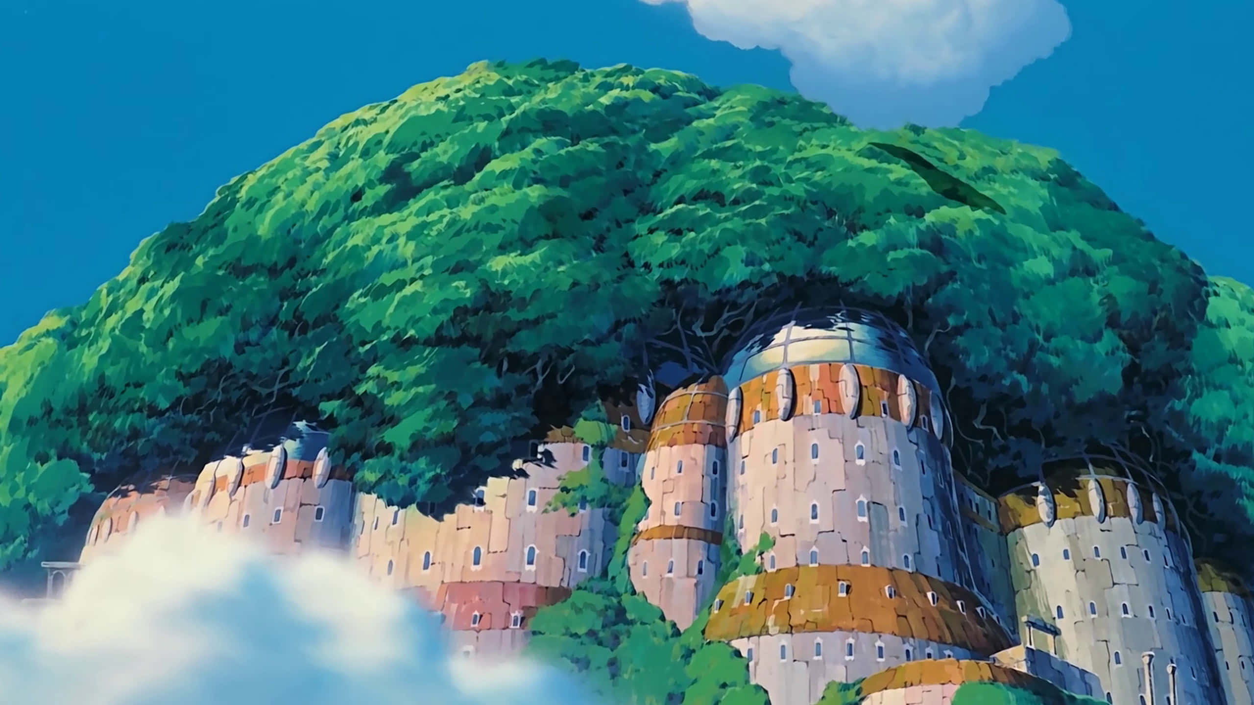 Studio Ghibli Art 桌布 壁紙 — 一座充滿活力的動漫城堡，坐落在巨大的綠色樹木下，樹葉茂密，藍天在上。