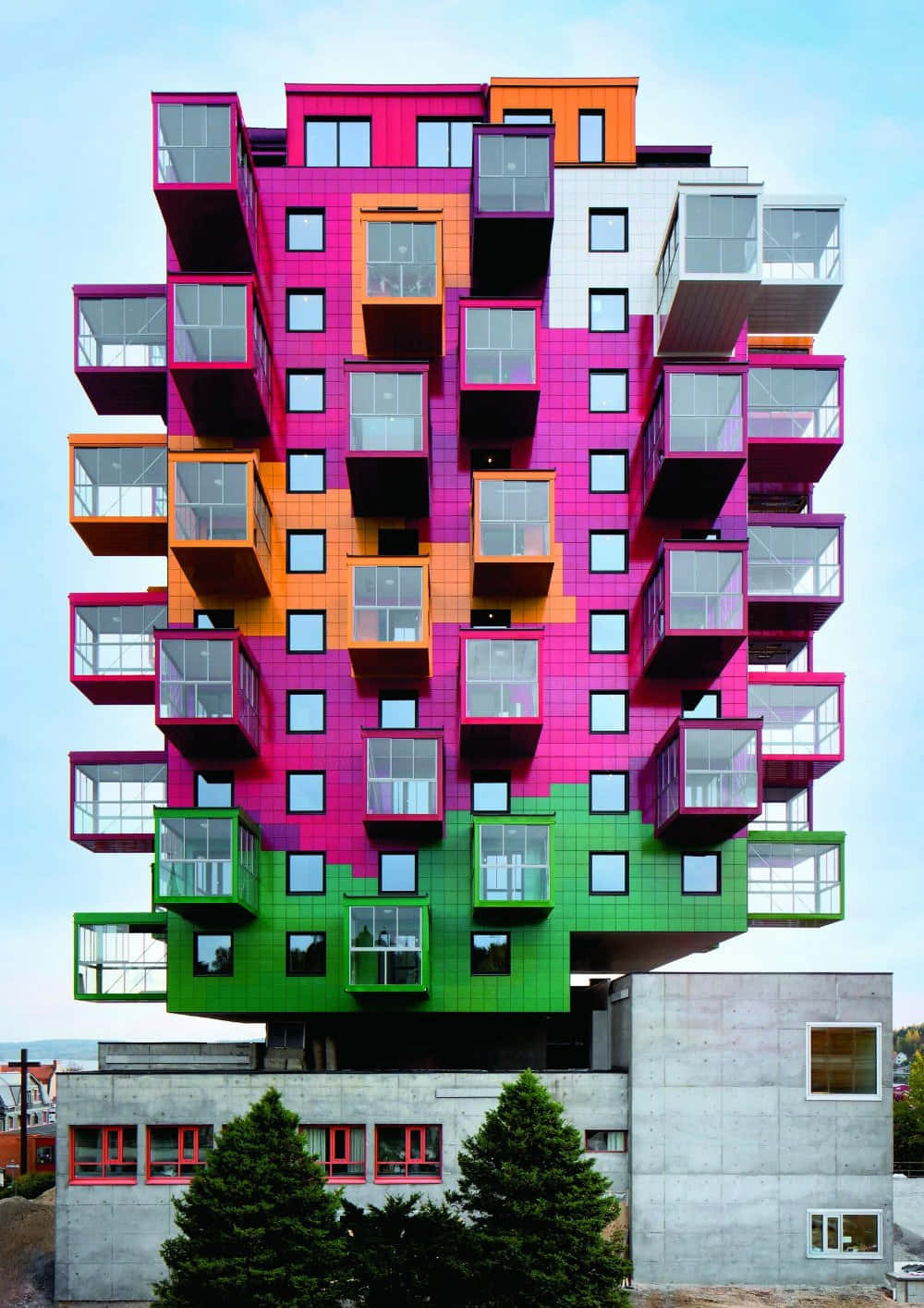 Postmodernism 桌布 壁紙 — 一座充滿活力的現代主義建築，堆疊著洋紅色、橙色和綠色的彩色立方體公寓，映襯著清澈的藍天。