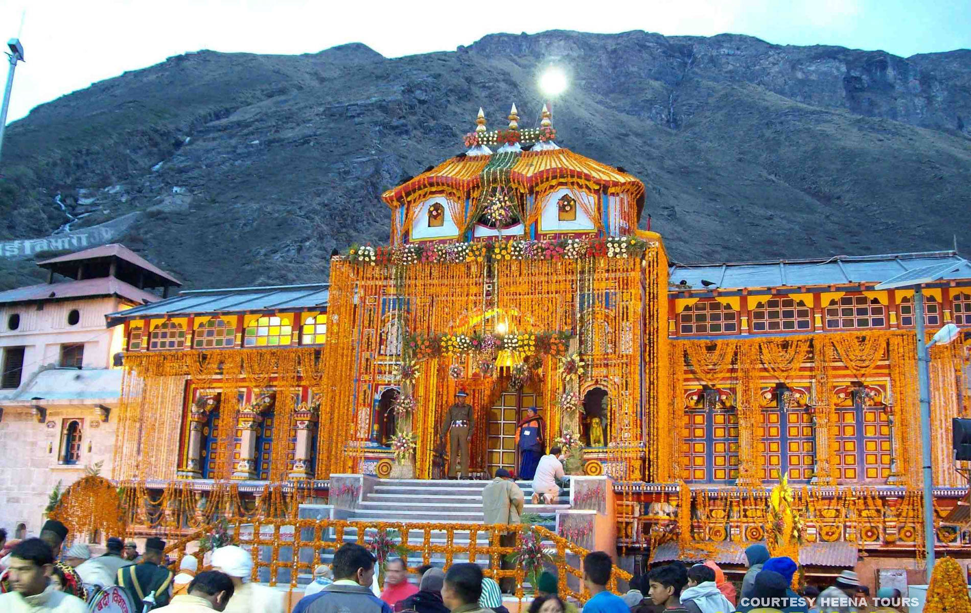 Kedarnath 桌布 壁紙 — 一座充滿活力的金色寺廟裝飾著花環，矗立在崎嶇的山脈前，信徒們聚集在入口處。