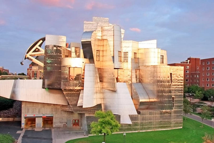 Minneapolis 桌布 壁紙 — 一座具有反光表面的未來感金屬建築，在柔和的藍天背景下於日落時分溫暖地發光。