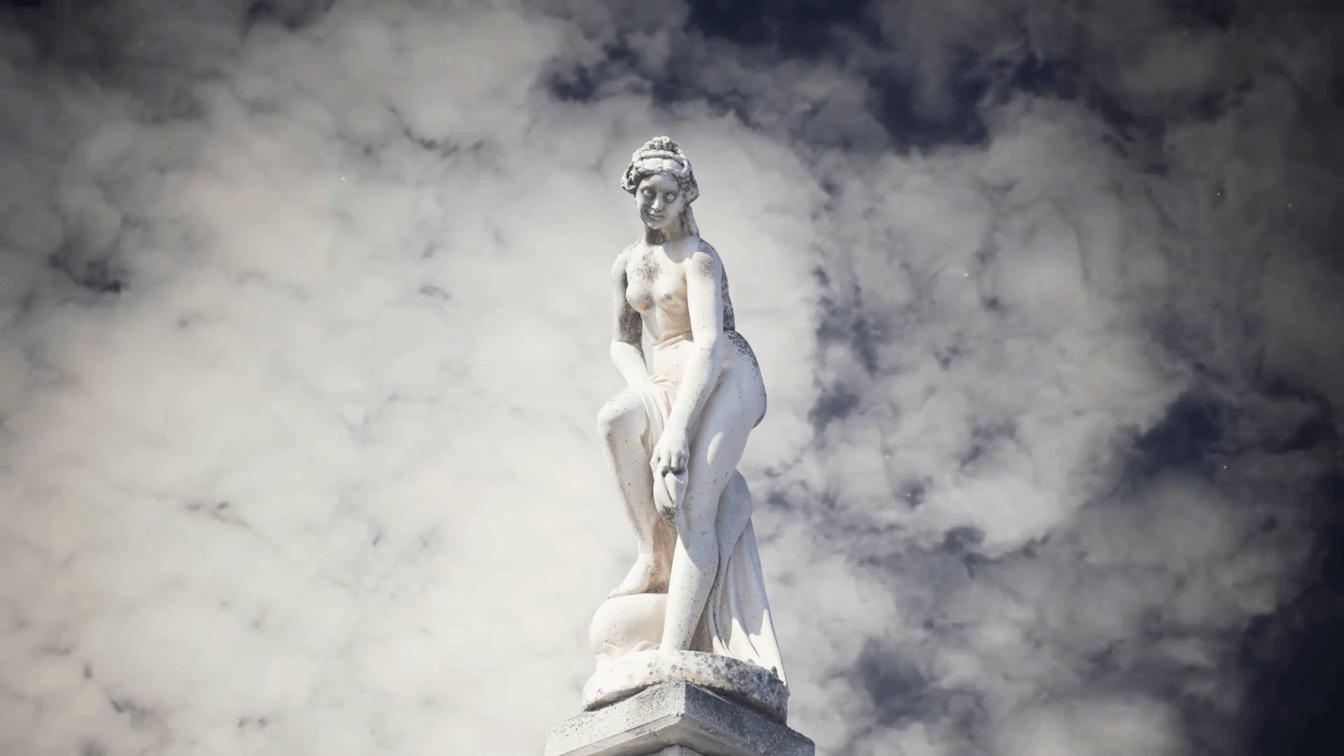 Statue Aesthetic 桌布 壁紙 — 一座古典白色大理石雕像，描繪一位坐著的女性，背景是戲劇性的多雲天空。
