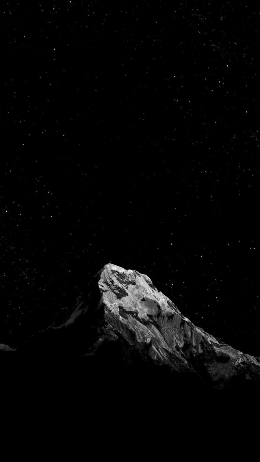 黑色 iPhone 桌布 桌布 壁紙 — 一座單色調的山峰在繁星點點的夜空下聳立，帶有深邃陰影和鋒利山脊。