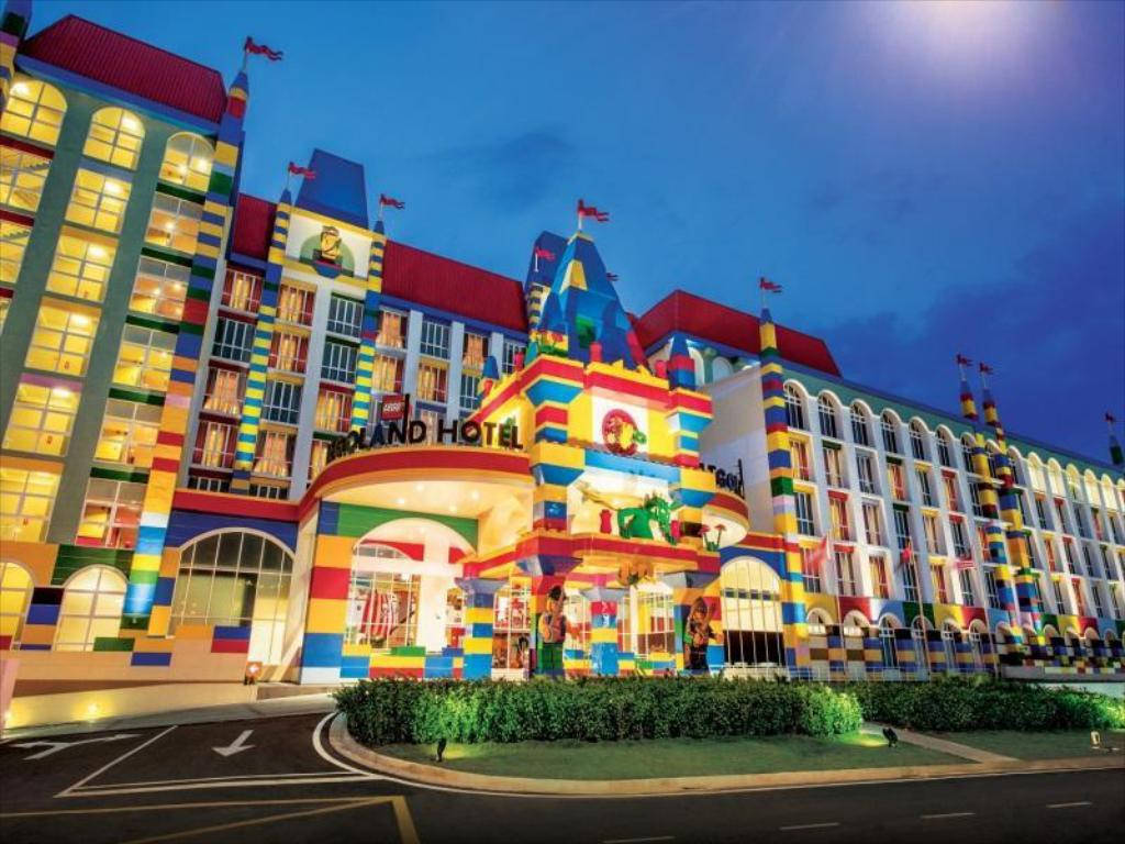 Hotel 桌布 壁紙 — 一座在黃昏時分明亮照明的樂高主題酒店建築，擁有色彩繽紛的積木建築和發光的窗戶。