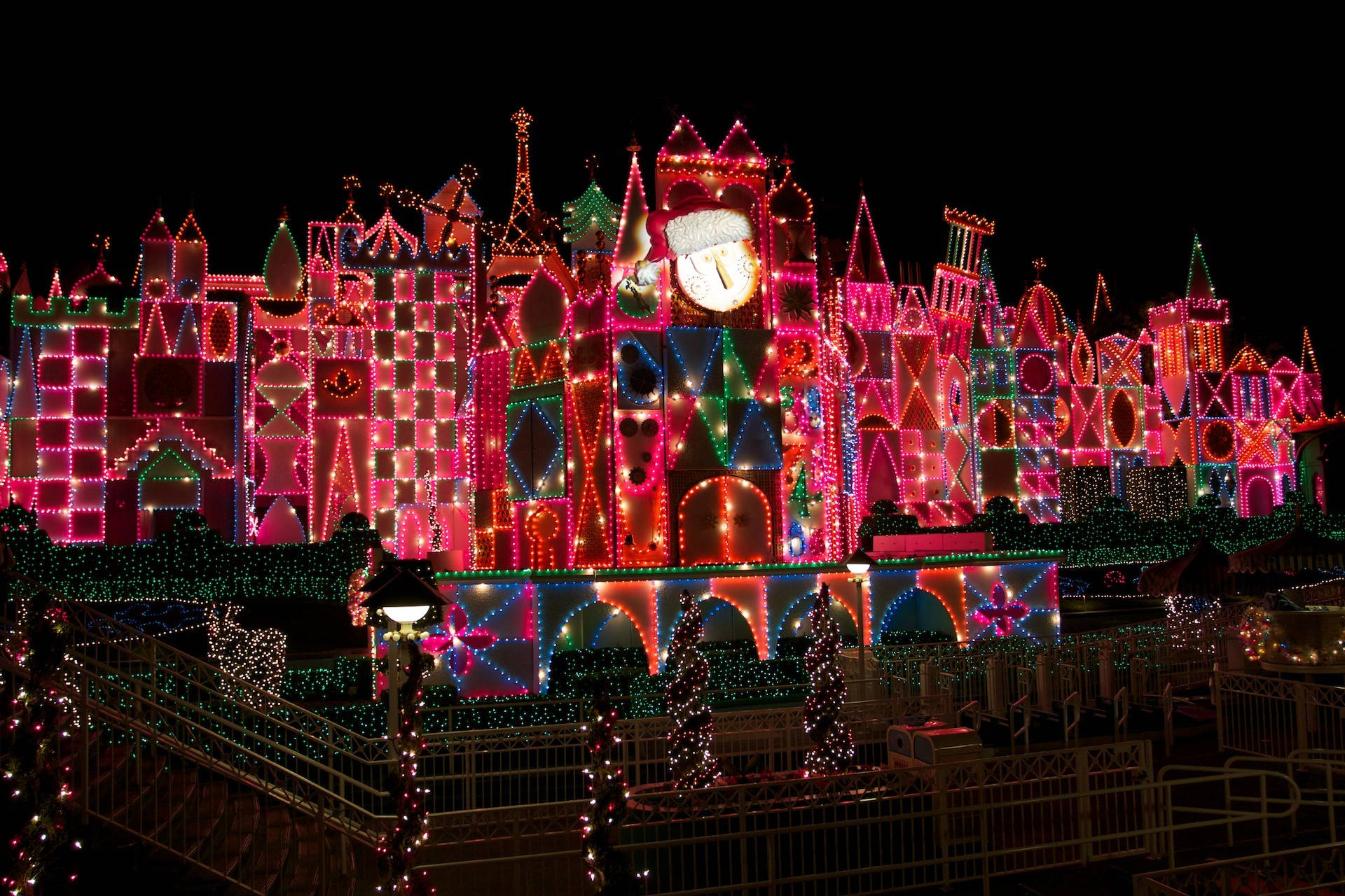 Disneyland Desktop 桌布 壁紙 — 一座城堡在夜間閃耀著鮮豔的粉紅色、綠色和藍色燈光，營造出神奇的節日氣氛。