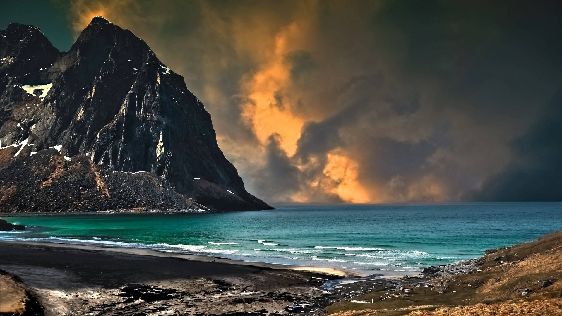 Beautiful Sky 桌布 壁紙 — 一座壯麗的山峰聳立在黑色沙灘之上，金色夕陽穿透烏雲，照耀在碧綠的海水上。
