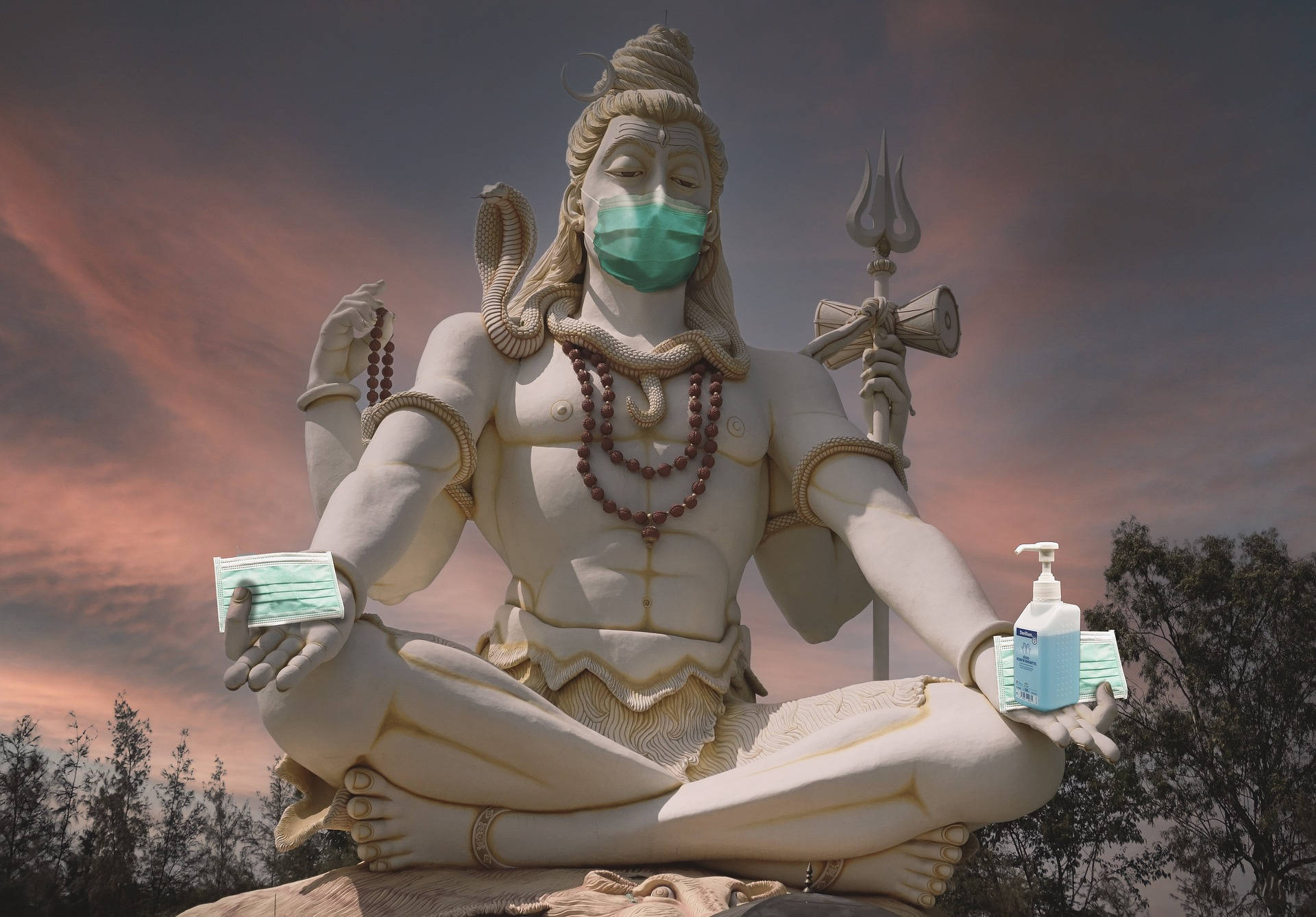 shiv shankar 桌布 壁紙 — 一座大型白色濕婆神像在暮色天空下平靜地冥想，同時戴著綠色口罩，手中拿著消毒搓手液和口罩。