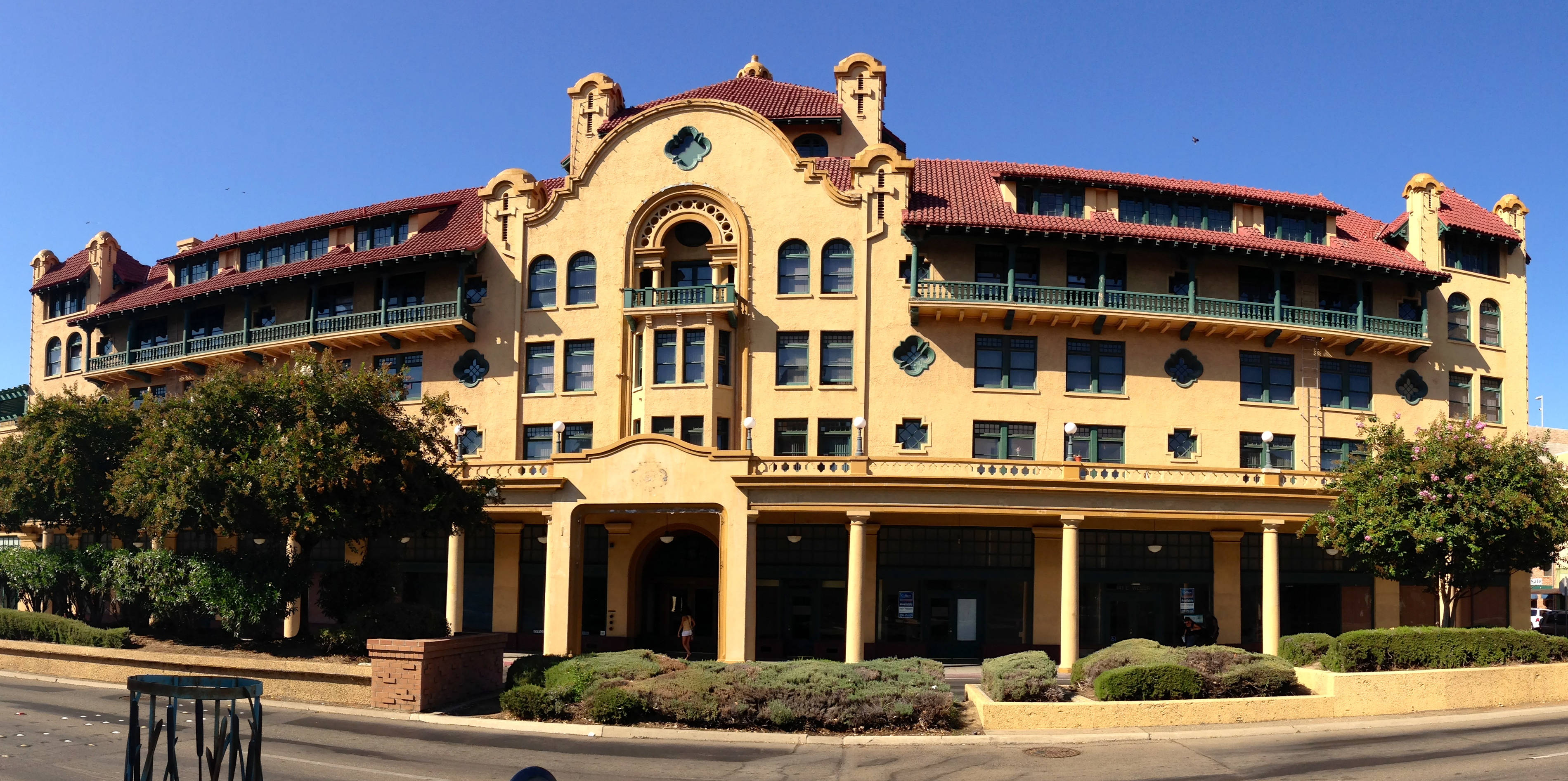 Hotel 桌布 壁紙 — 一座大型米色西班牙復興風格建築，擁有紅色瓦片屋頂和拱形窗戶，矗立在清澈的藍天下。