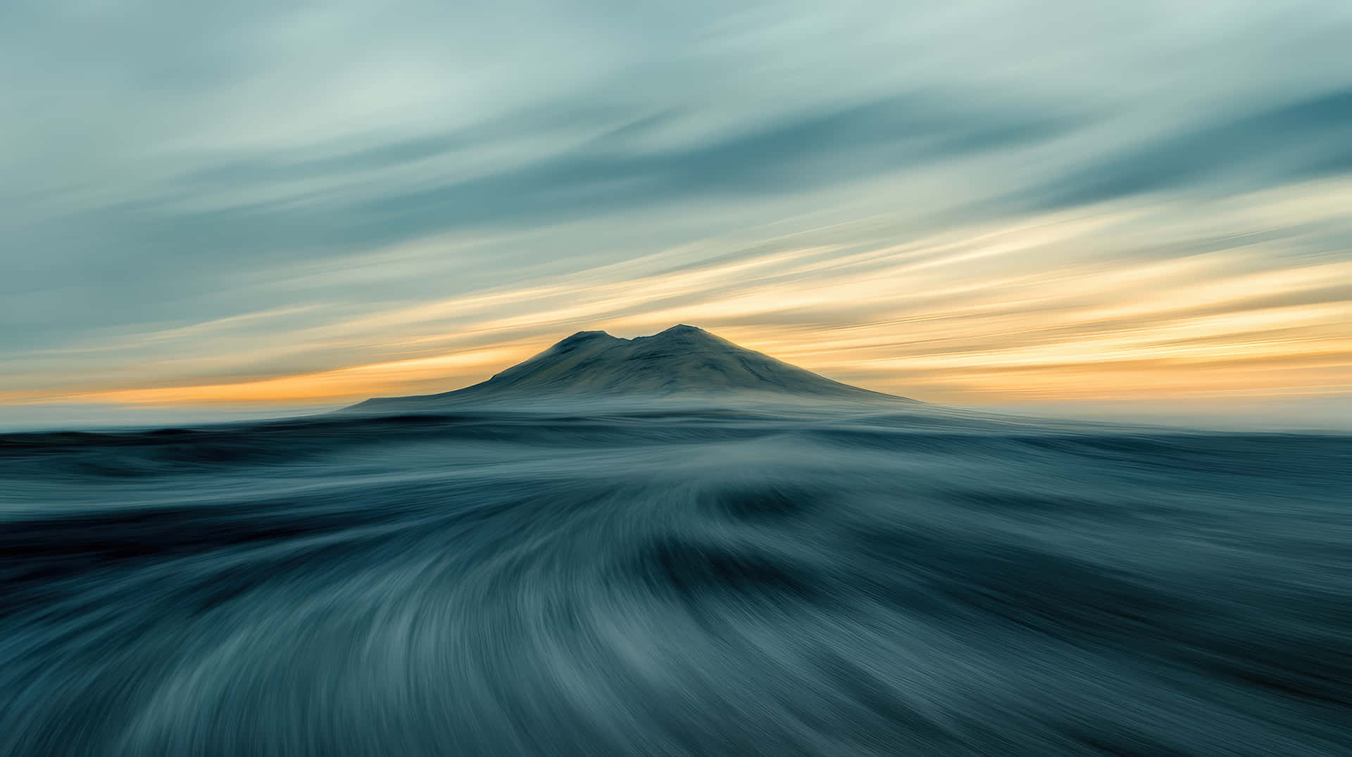 Surreal Mountain Landscape with Motion Blur and Dramatic Sky at Sunset 壁紙 — 一座孤獨的山從漩渦般的海洋中升起，天空佈滿金色和藍綠色的條紋，呈現暮色。