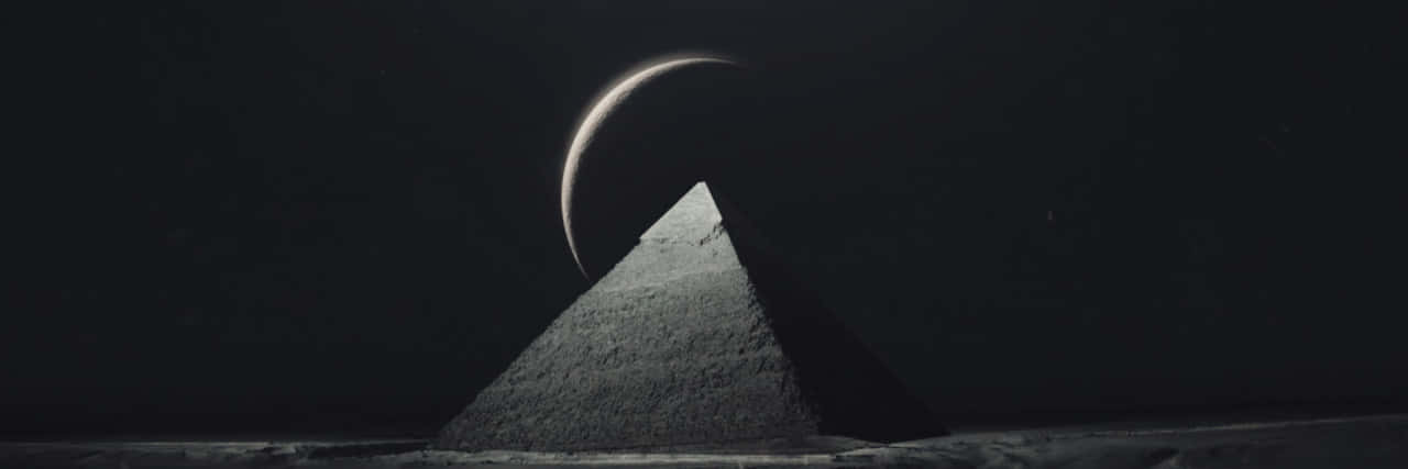 Moon Aesthetic 桌布 壁紙 — 一座孤獨的金字塔矗立在嚴峻的黑白沙漠景觀中，新月之下。