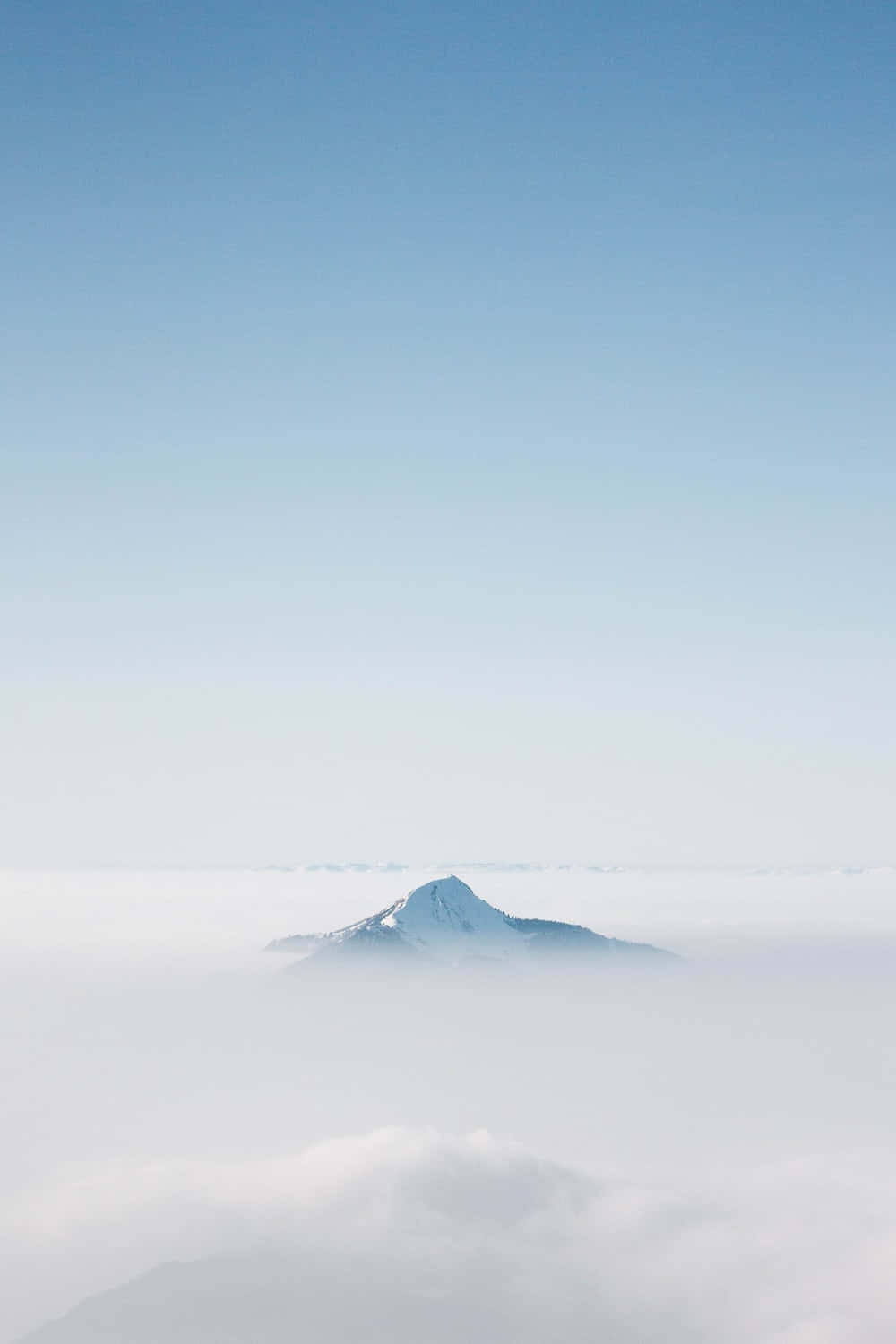 淺藍色美學動圖 桌布 壁紙 — 一座孤獨的雪山頂峰在清澈藍天下，從柔軟白雲海中雄偉地升起。