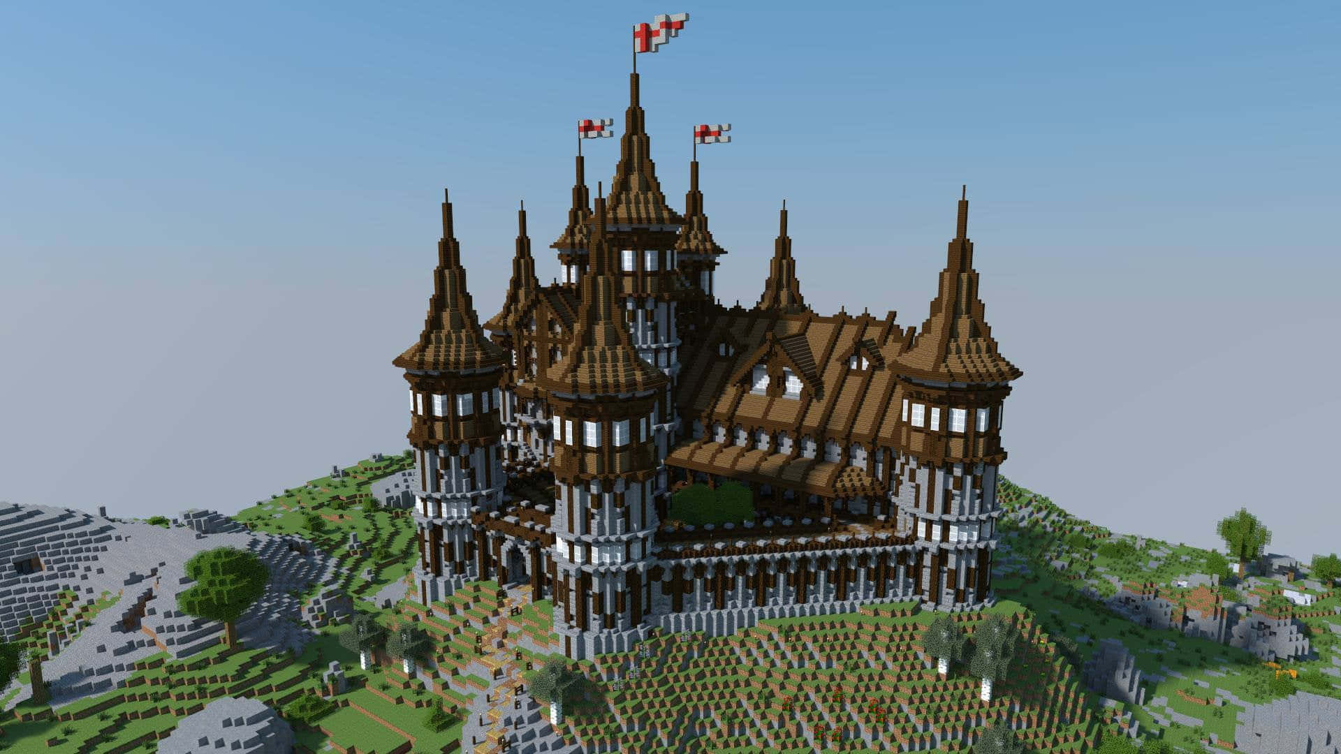 Minecraft Castles 桌布 壁紙 — 一座宏偉的中世紀城堡，擁有棕色屋頂和白色石塔，矗立在一個方塊狀的Minecraft景觀中的草丘上，天空清澈湛藍。