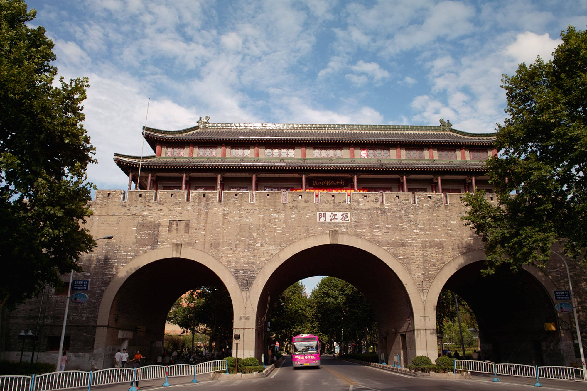 Nanjing 桌布 壁紙 — 一座宏偉的傳統中國城門，有三個拱門，矗立在點綴著蓬鬆白雲的明亮藍天下。