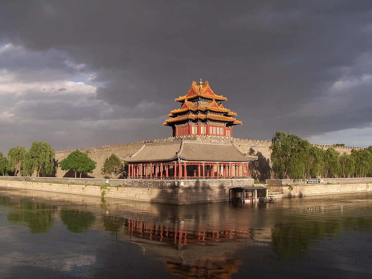 reflection 桌布 壁紙 — 一座宏偉的傳統中國宮殿塔樓，紅色柱子與金色屋頂，在平靜的水面上倒映，背景是戲劇性的暴風雨天空。