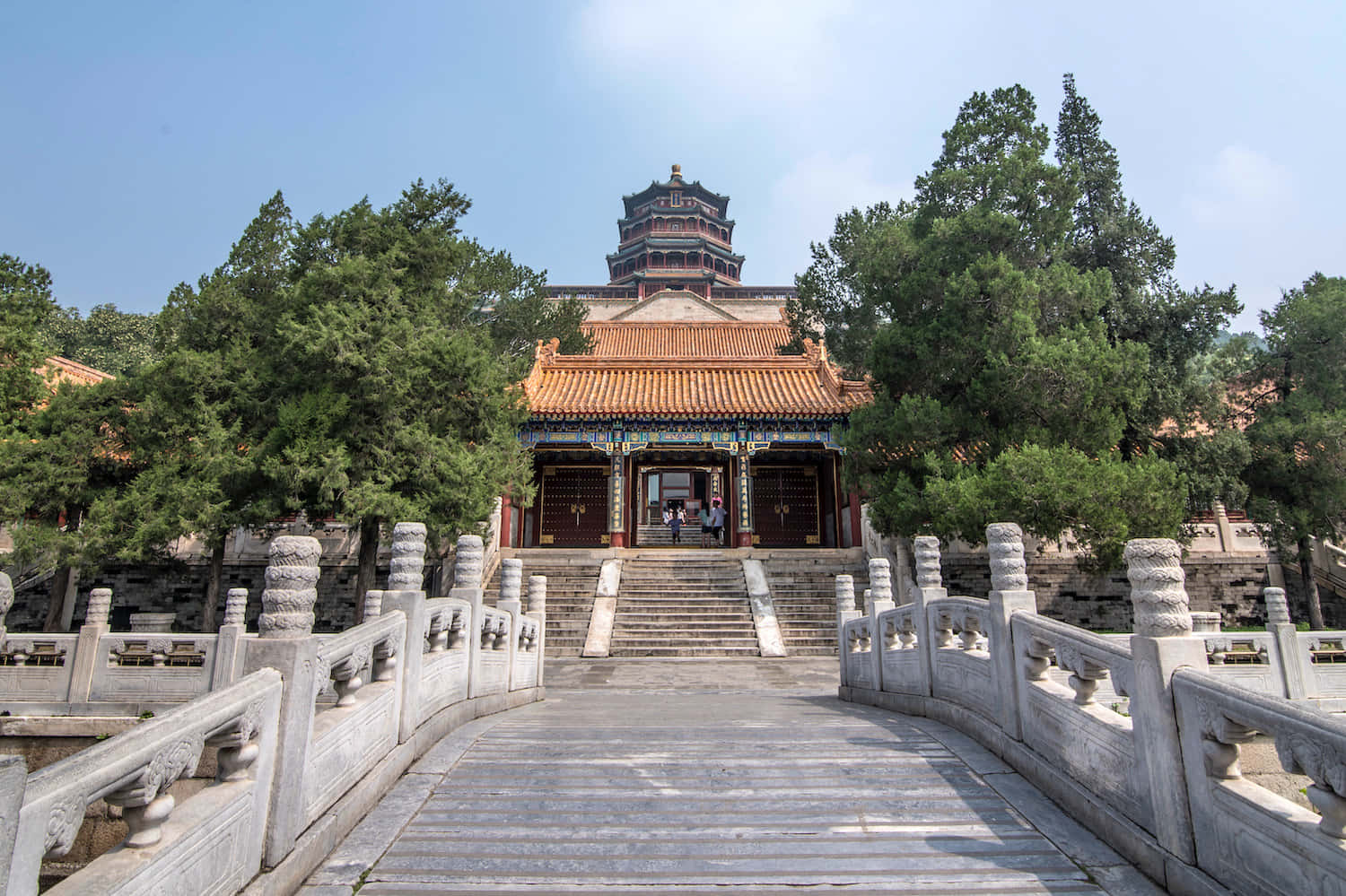 建築 桌布 壁紙 — 一座宏偉的傳統中國寺廟，擁有橙色瓦頂和石橋，在清澈的藍天下。