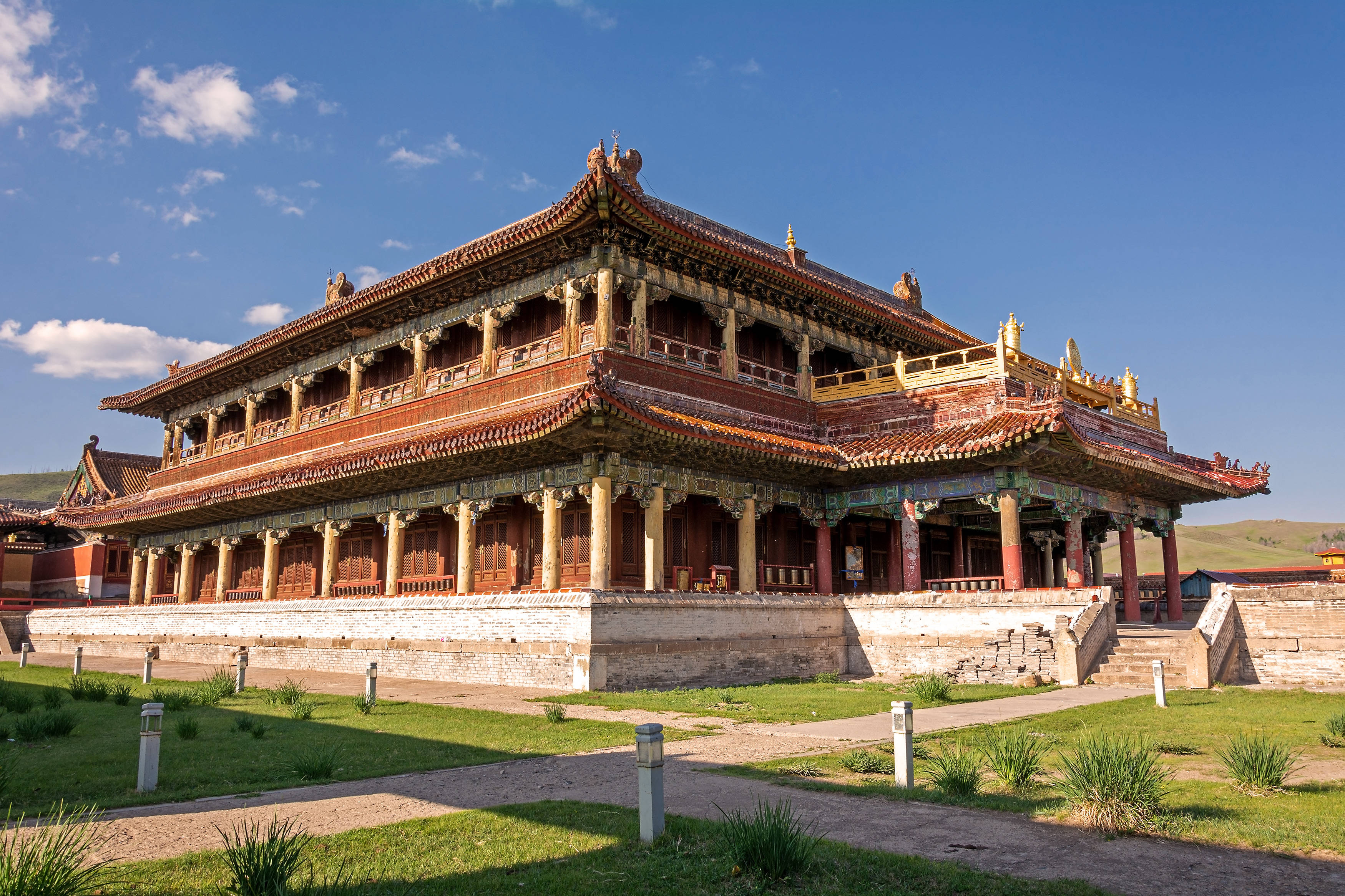 蒙古 桌布 壁紙 — 一座宏偉的傳統中國寺廟，擁有華麗的紅色和金色屋頂，矗立在晴朗的藍天和白雲之下。