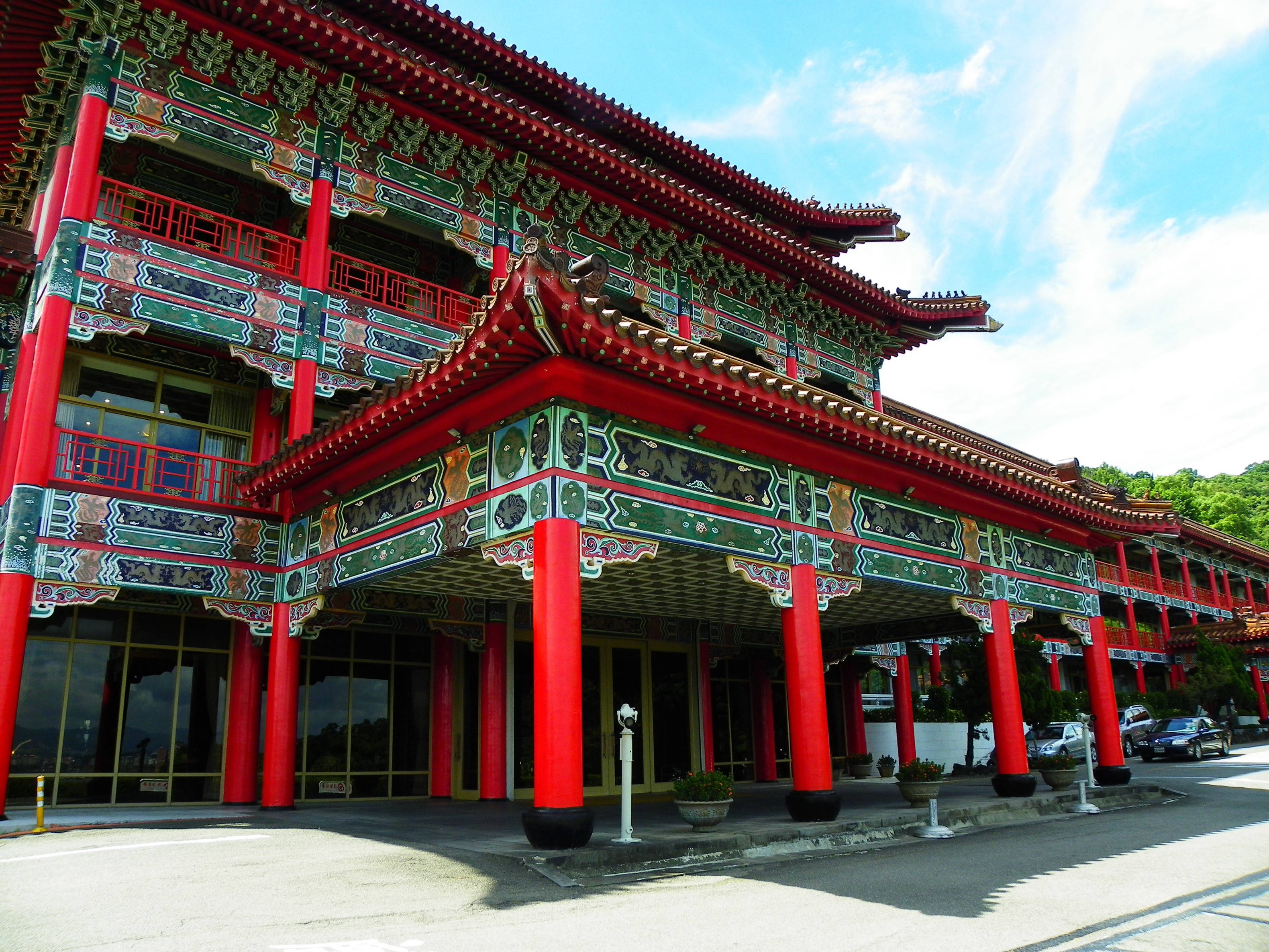 台北 桌布 壁紙 — 一座宏偉的傳統中國寺廟，擁有鮮紅色的柱子和華麗的綠色屋頂邊緣，在明亮的藍天下。