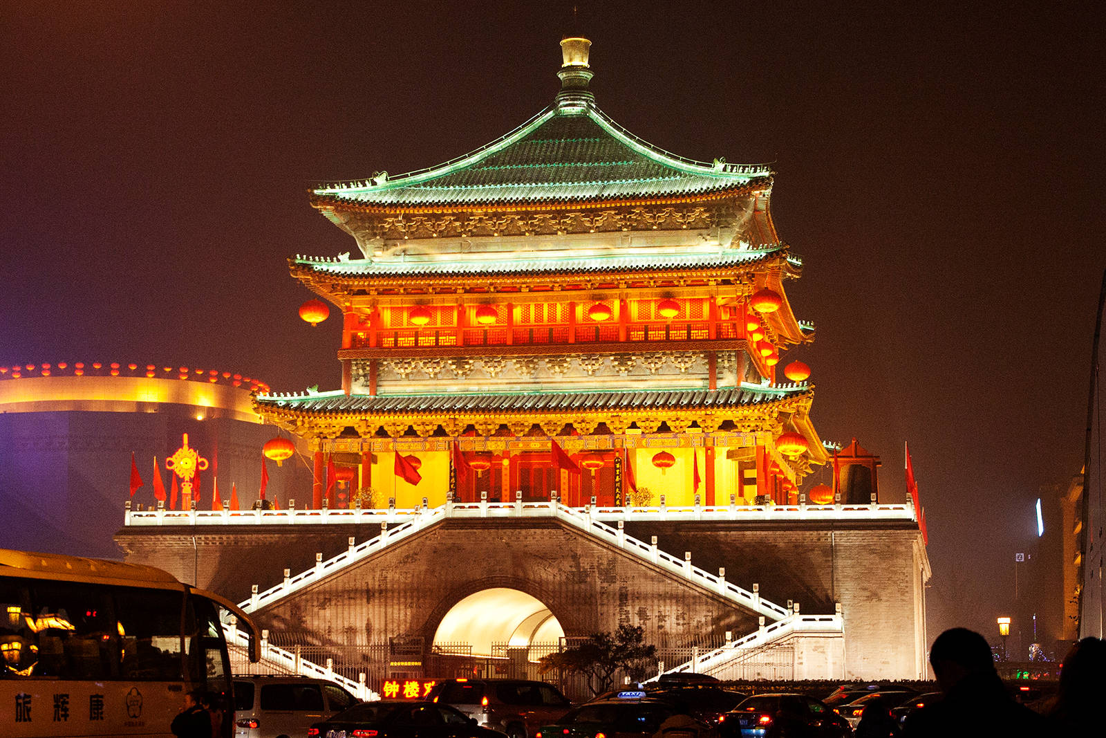Xian 桌布 壁紙 — 一座宏偉的傳統中式塔樓，在深色夜空下以溫暖的橙色和綠色燈光照亮，下方車水馬龍。