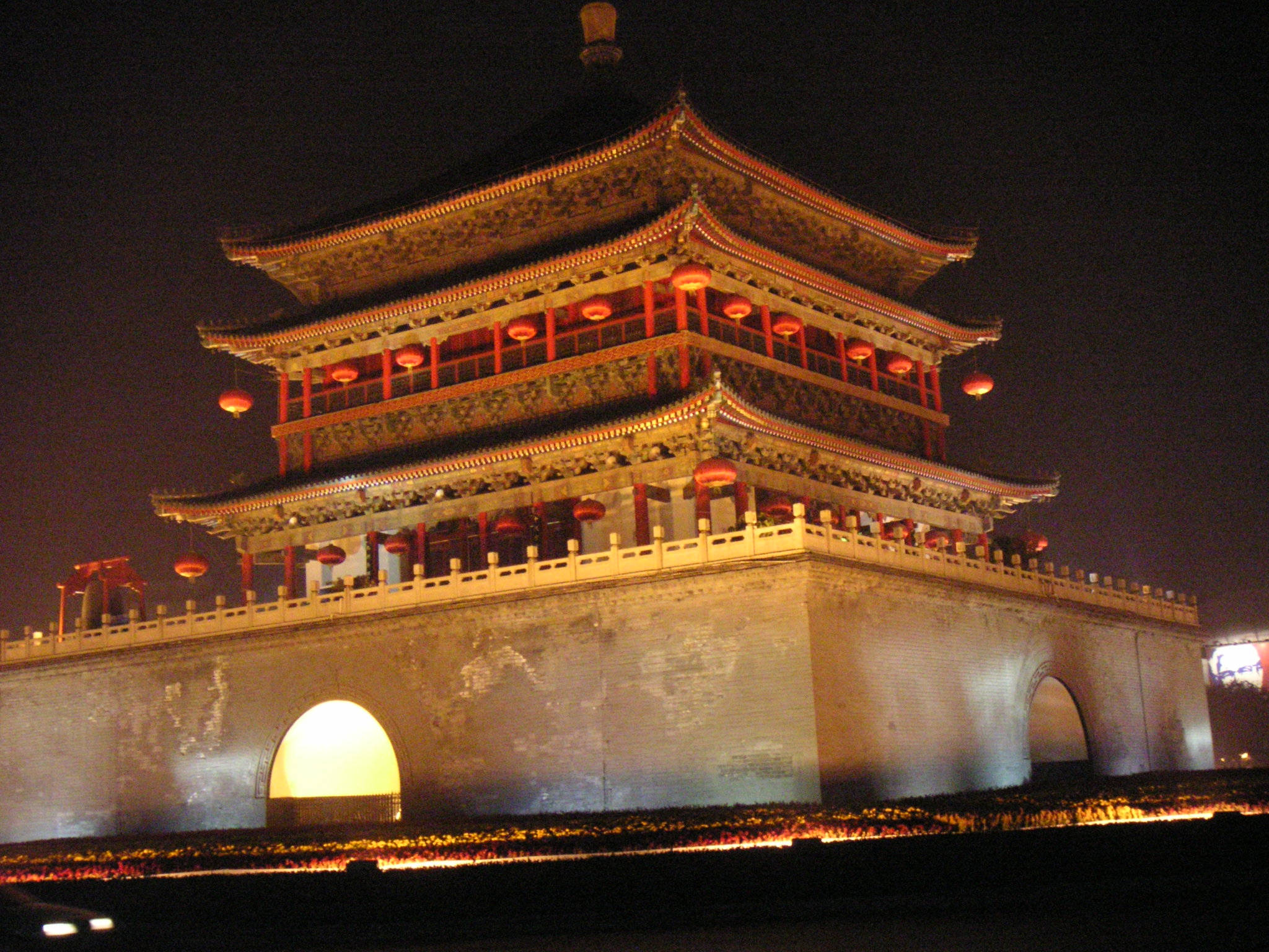 Xian 桌布 壁紙 — 一座宏偉的傳統中式塔樓在夜晚被紅色燈籠和溫暖的金色燈光照亮，映襯著黑暗的天空。