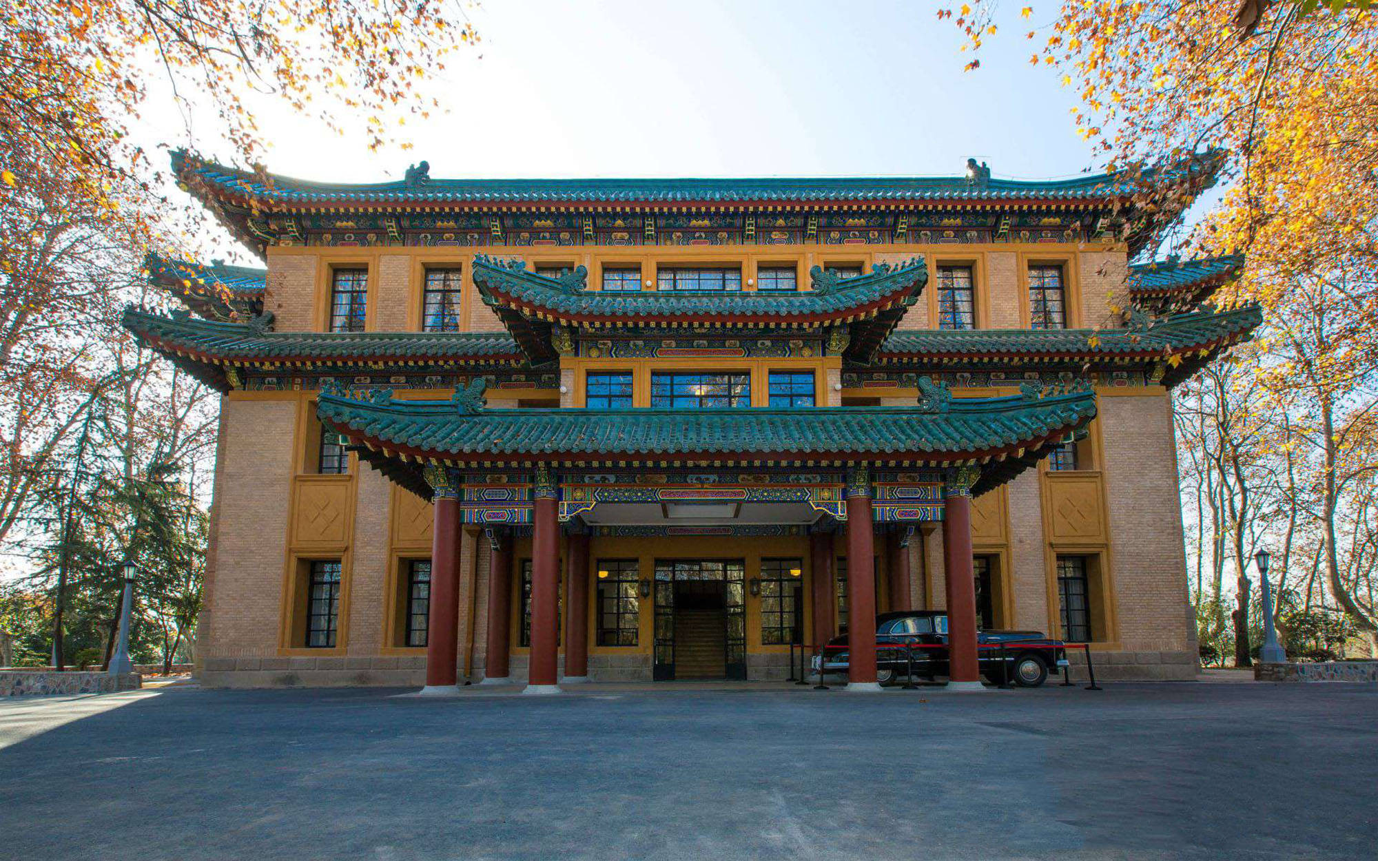 Nanjing 桌布 壁紙 — 一座宏偉的傳統中式建築，擁有青綠色屋頂和紅色柱子，矗立在秋樹下，樹葉金黃。