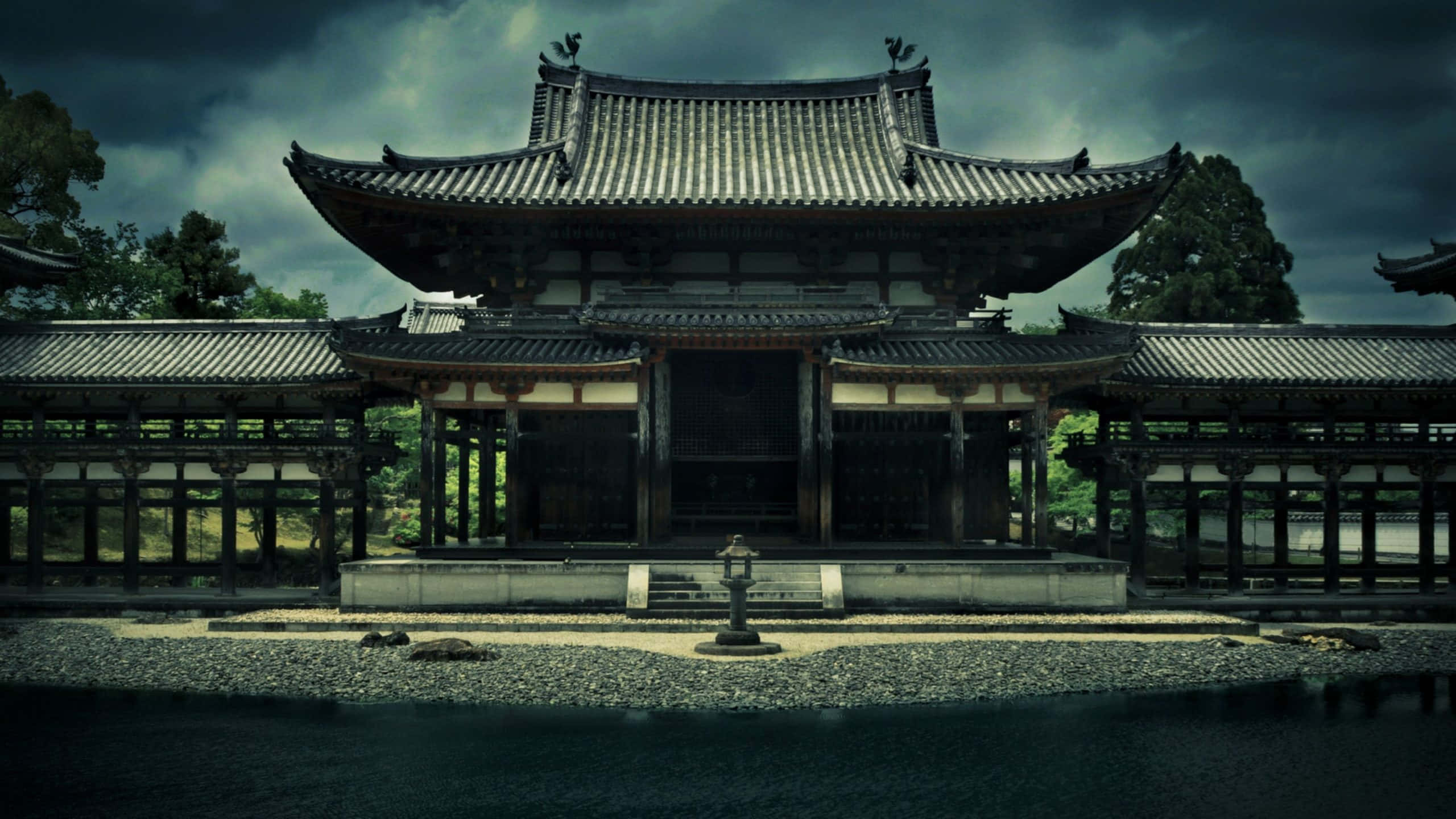 日本 桌布 壁紙 — 一座宏偉的傳統日本寺廟，擁有寬闊的瓦片屋頂，在陰沉暴風雨的天空下莊嚴矗立。