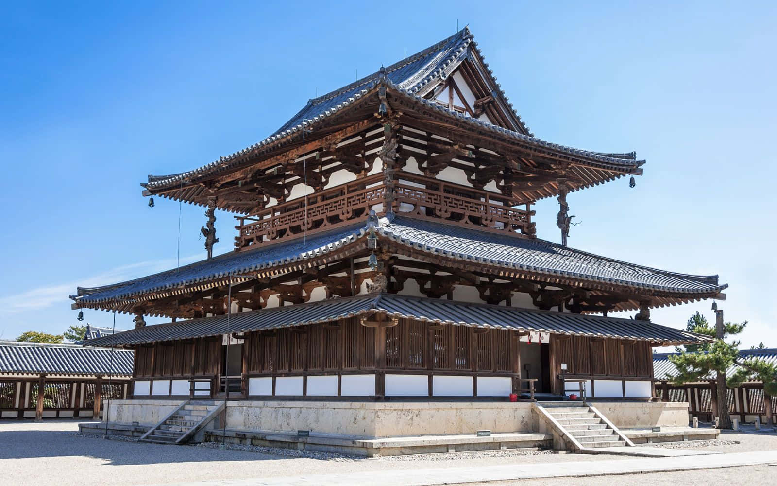 日式 桌布 壁紙 — 一座宏偉的傳統日本寺廟，擁有層疊的木造屋頂和瓦片屋簷，矗立在清澈的藍天下。