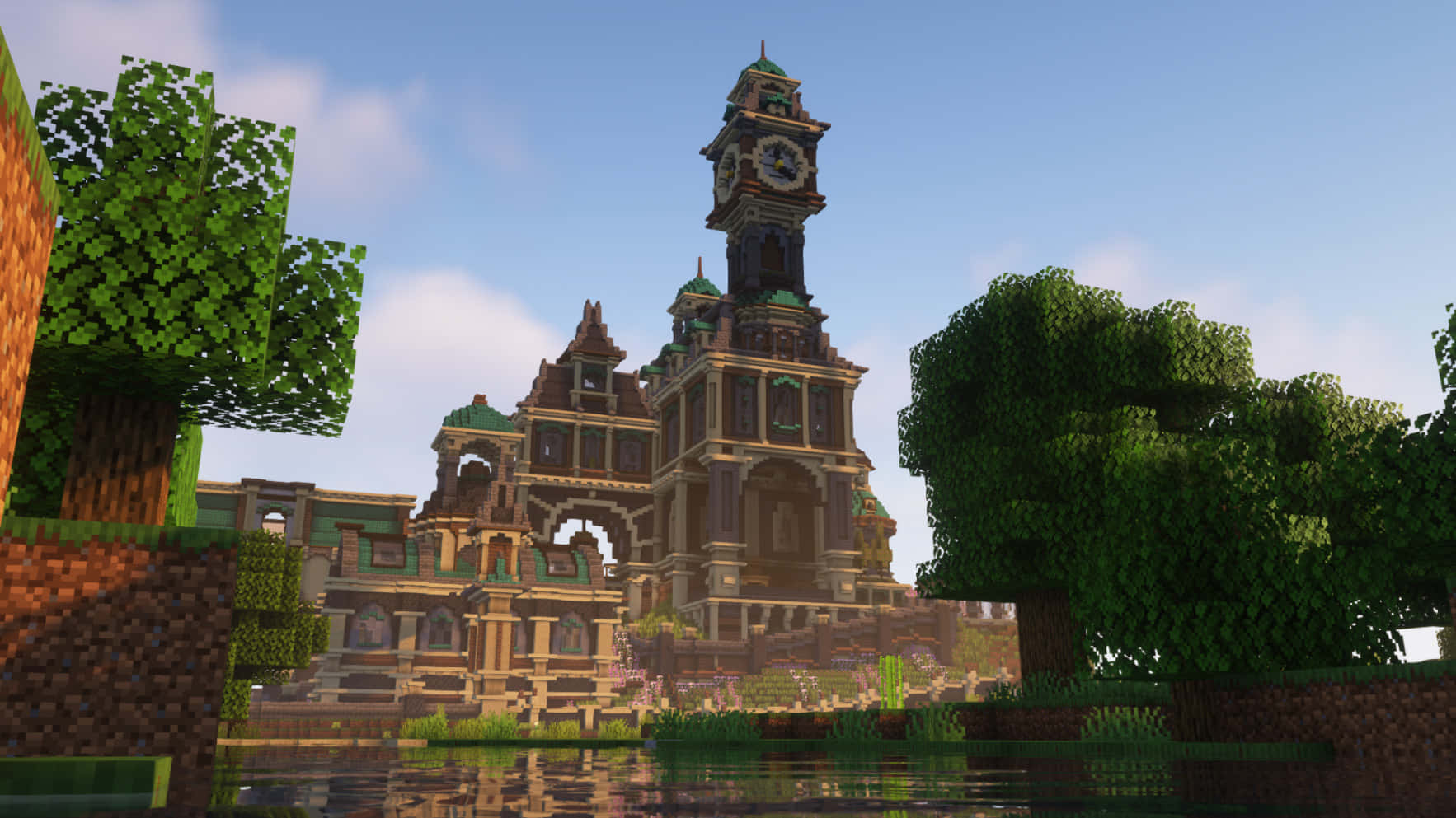 Minecraft Castles 桌布 壁紙 — 一座宏偉的像素化鐘樓，擁有綠色屋頂和拱形窗戶，矗立在清澈藍天下的反射池塘旁。