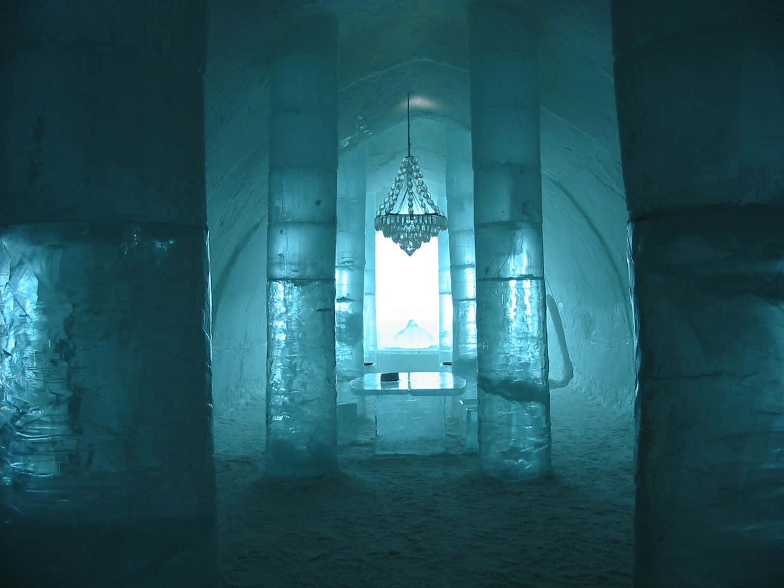 Ice Hotel 桌布 壁紙 — 一座宏偉的冰造大教堂，高聳的柱子和吊燈在冷藍光中柔和發光。